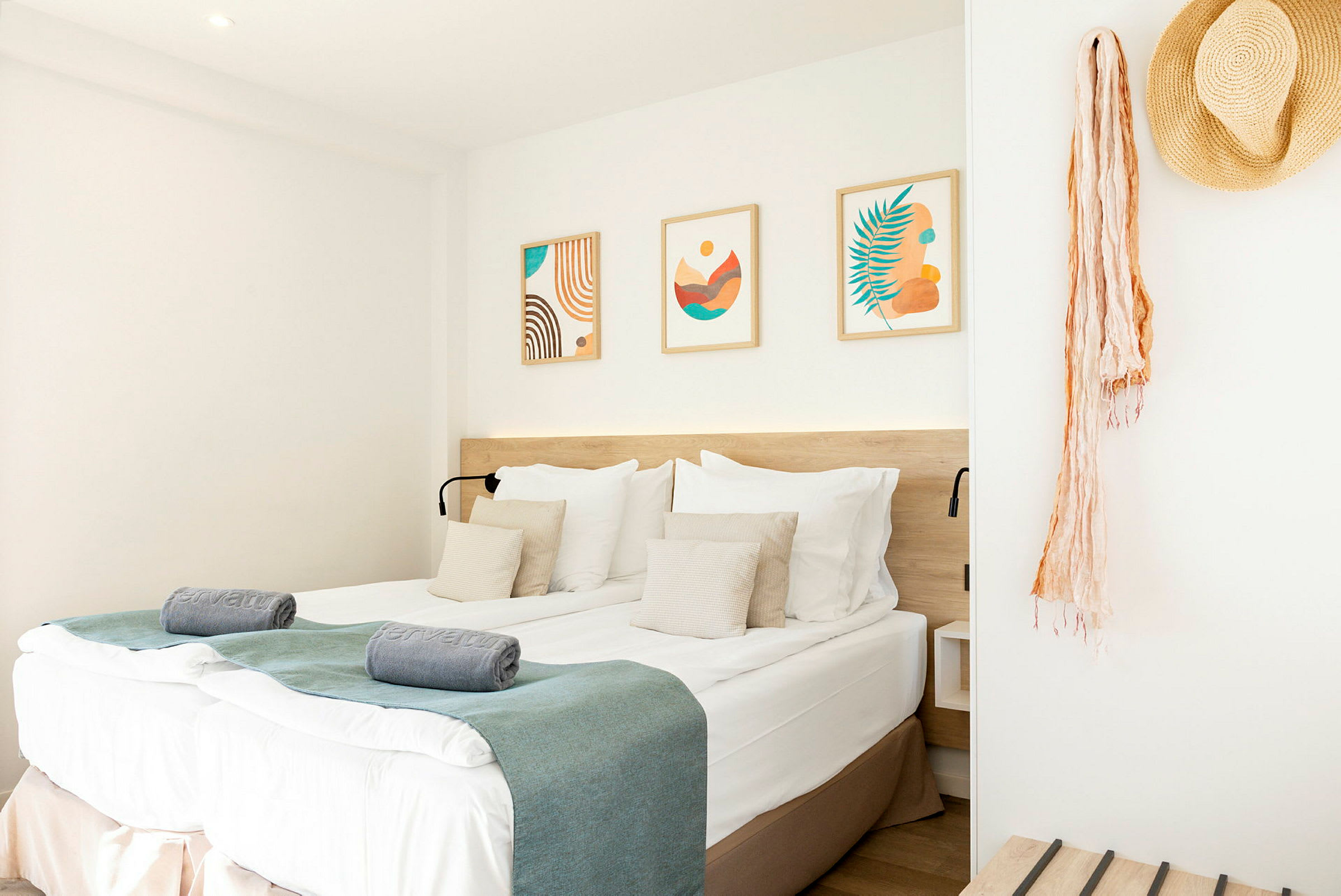 Et hotellrom med en dobbeltseng, dekorerte puter og kunstverk på veggen. (AI-generert tekst)