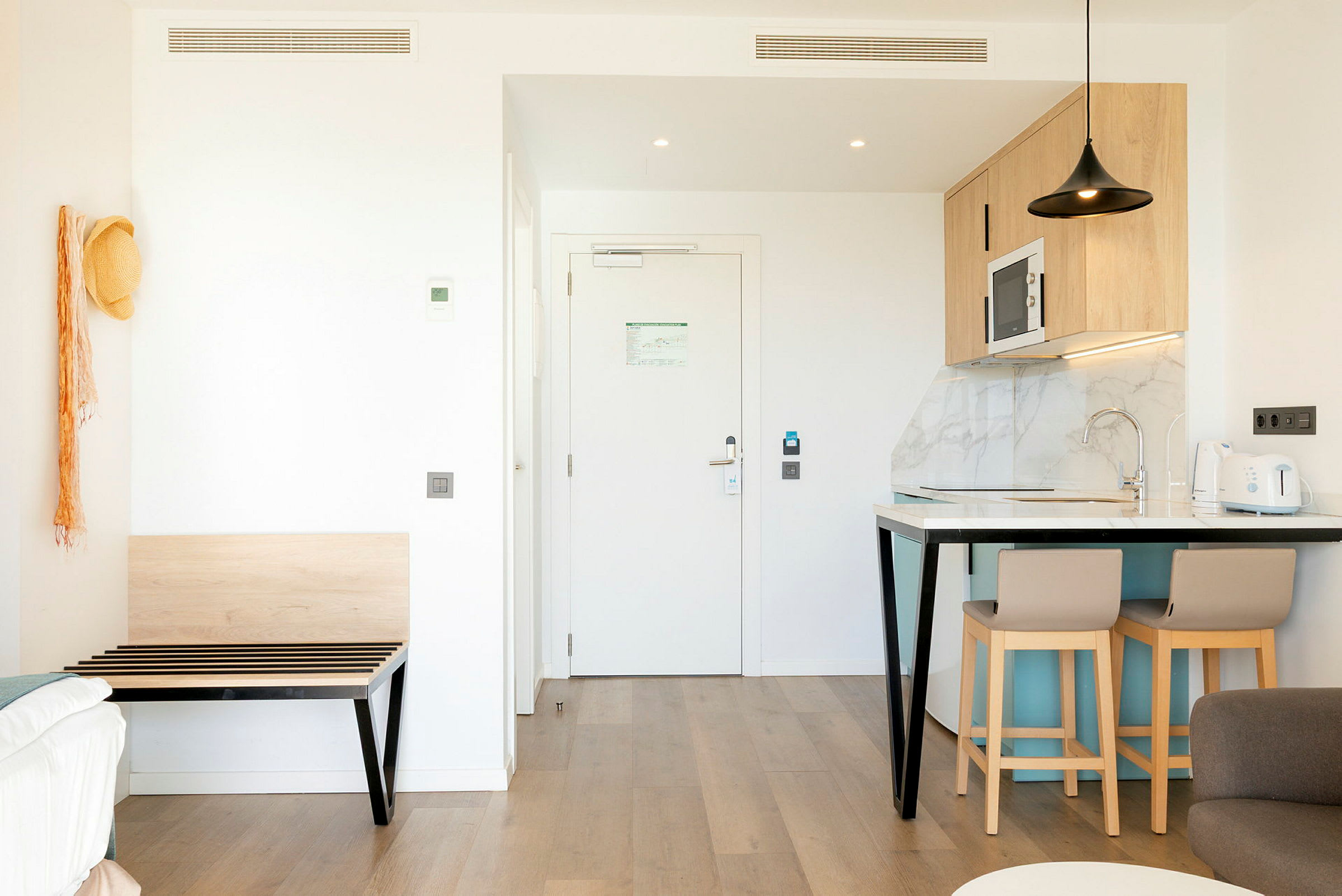 Bilde av et moderne hotellrom med kjøkkenområde og inngang. (AI-generert tekst)