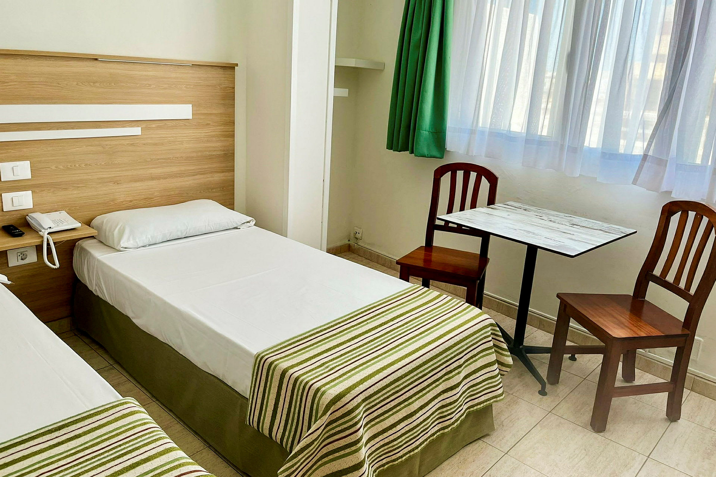 To enkeltsenger på et hotellrom med et bord og to stoler. (AI-generert tekst)