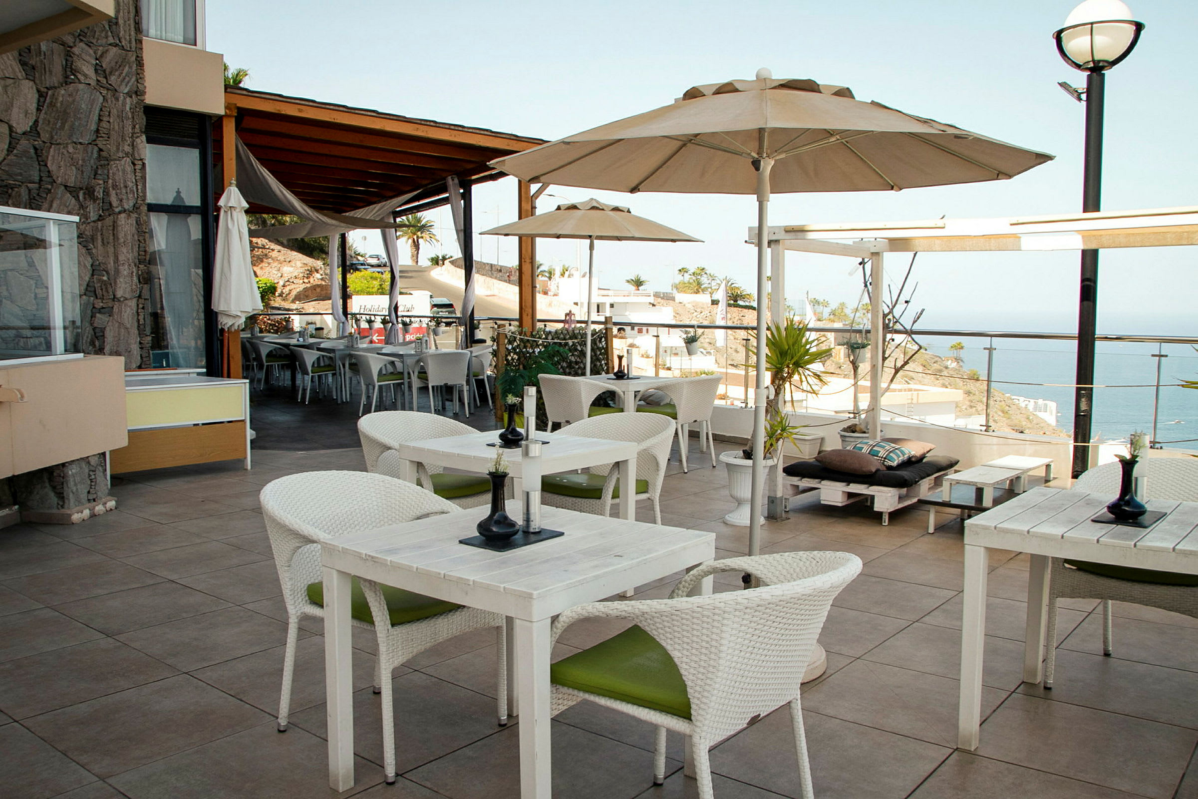 En terrasse med bord og stoler samt utsikt over havet. (AI-generert tekst)