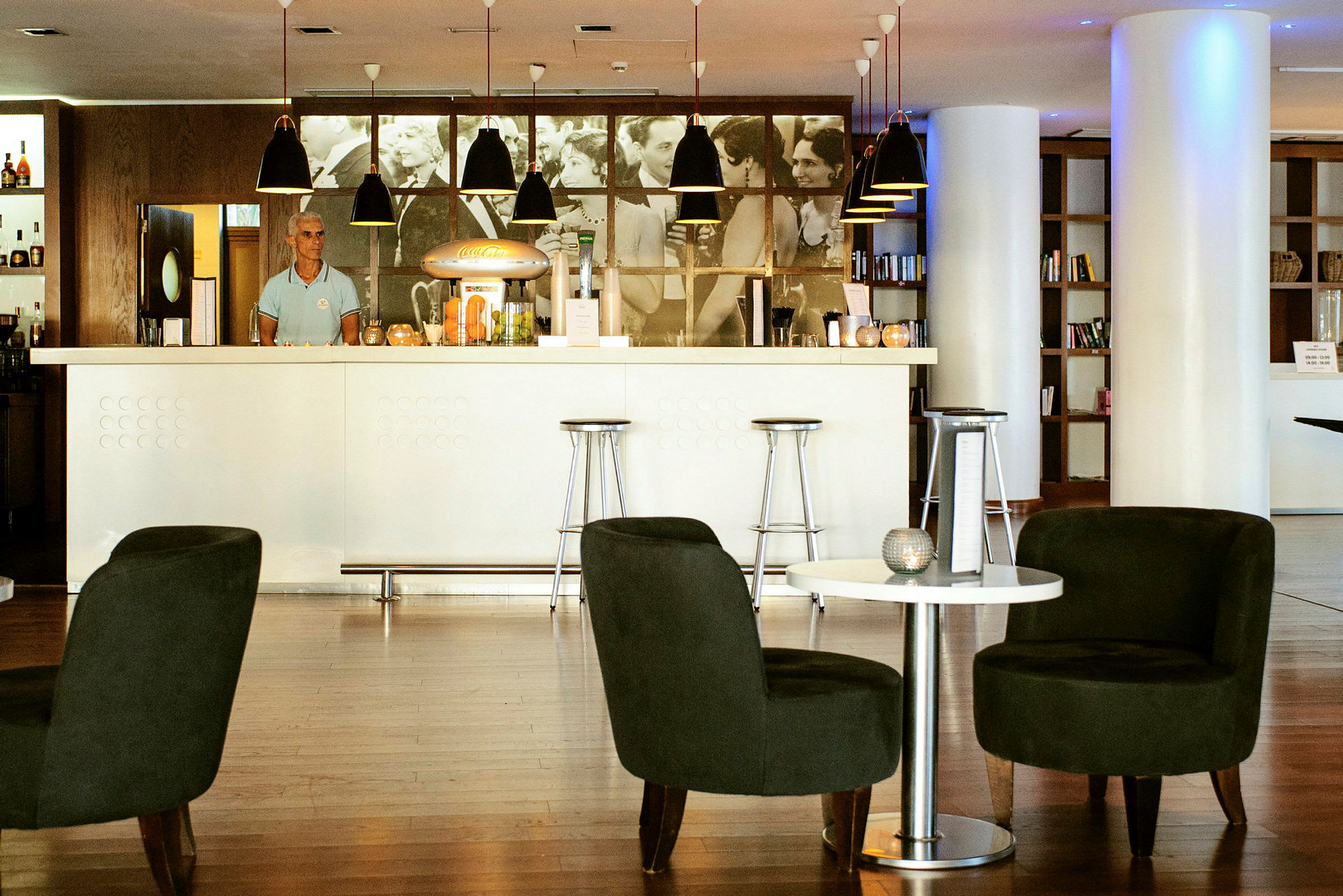 Moderne bar med hvite og mørke møbler samt en hylle med bøker i bakgrunnen. (AI-generert tekst)