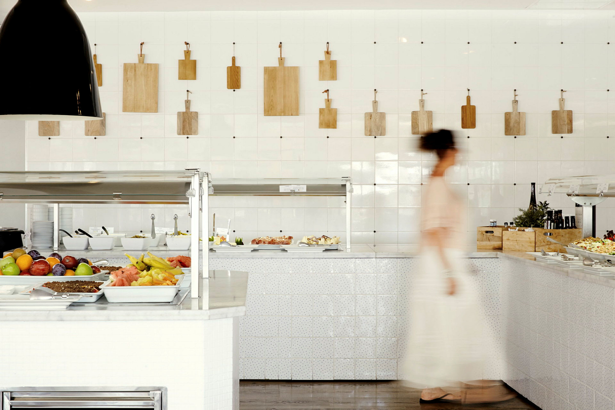 Bilde av et buffetområde med frukt og salat, en person passerer. (AI-generert tekst)