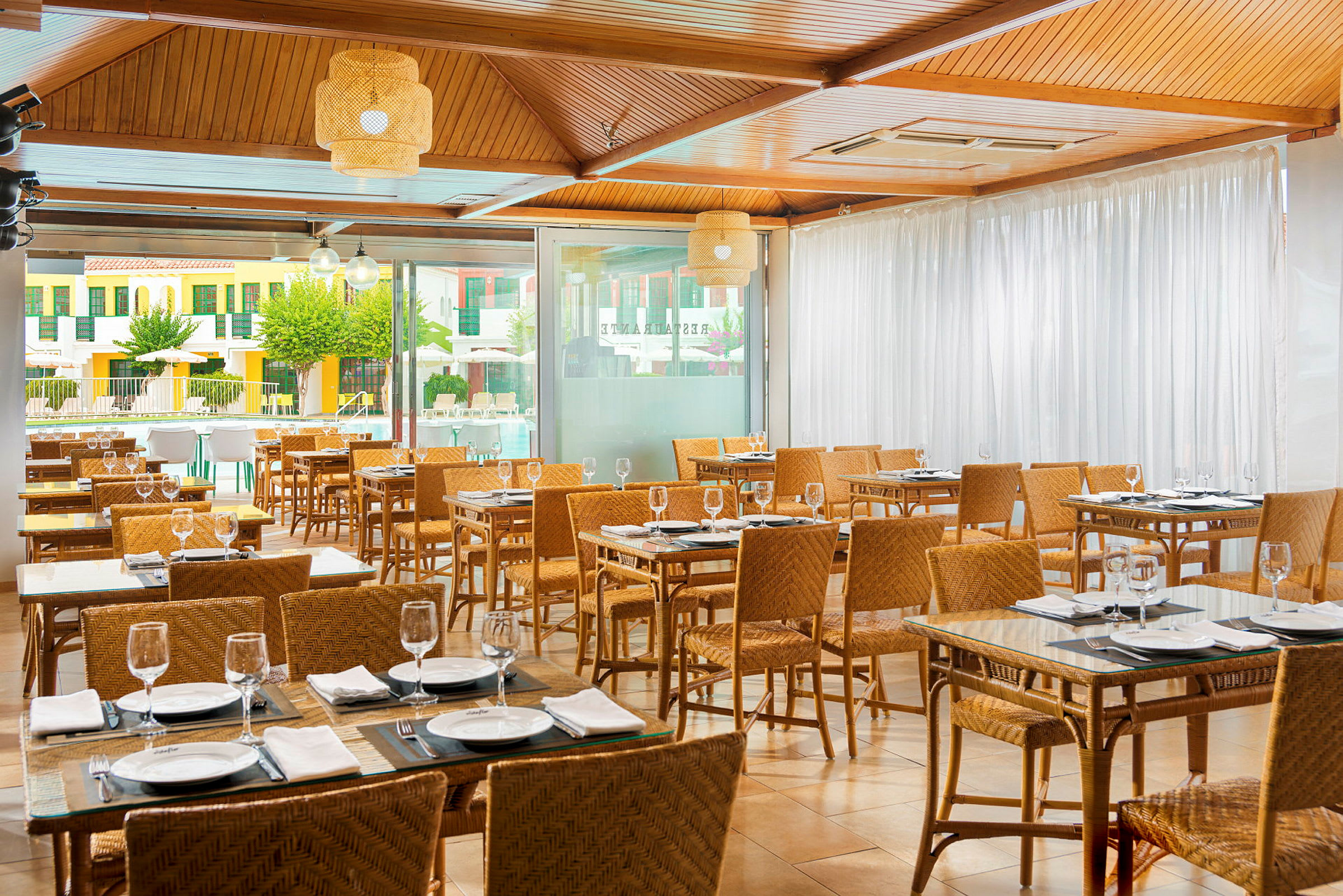 Innendørs restaurant med dekkede bord og rottingstoler. (AI-generert tekst)