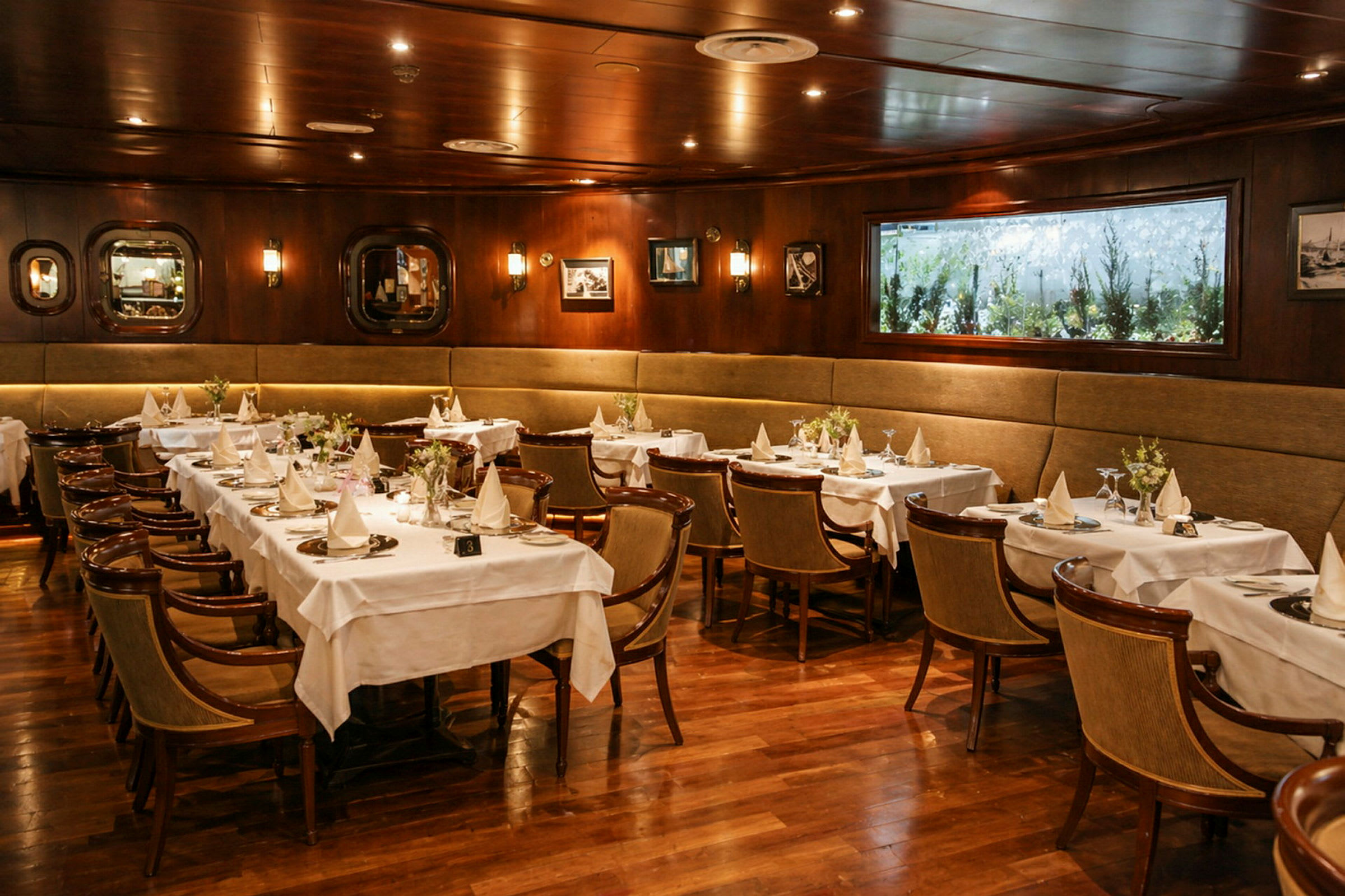 En elegant restaurantlokale med treinteriør, dekket med hvite duker og stoler ordnet rundt. (AI-generert tekst)