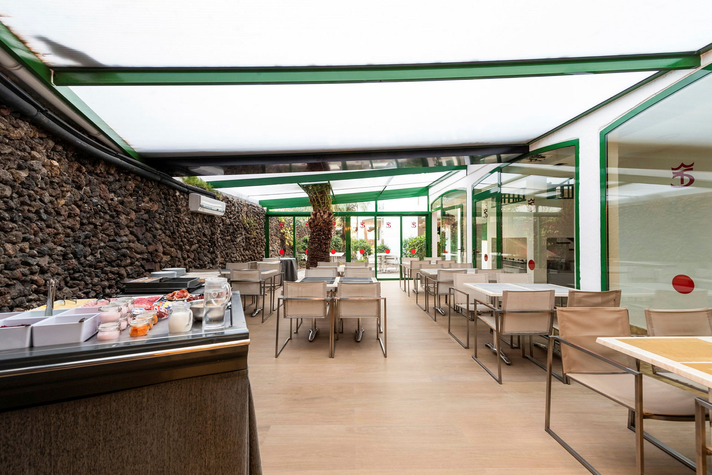 Spiseområde med bord og stoler under tak samt en frokostbuffet. (AI-generert tekst)