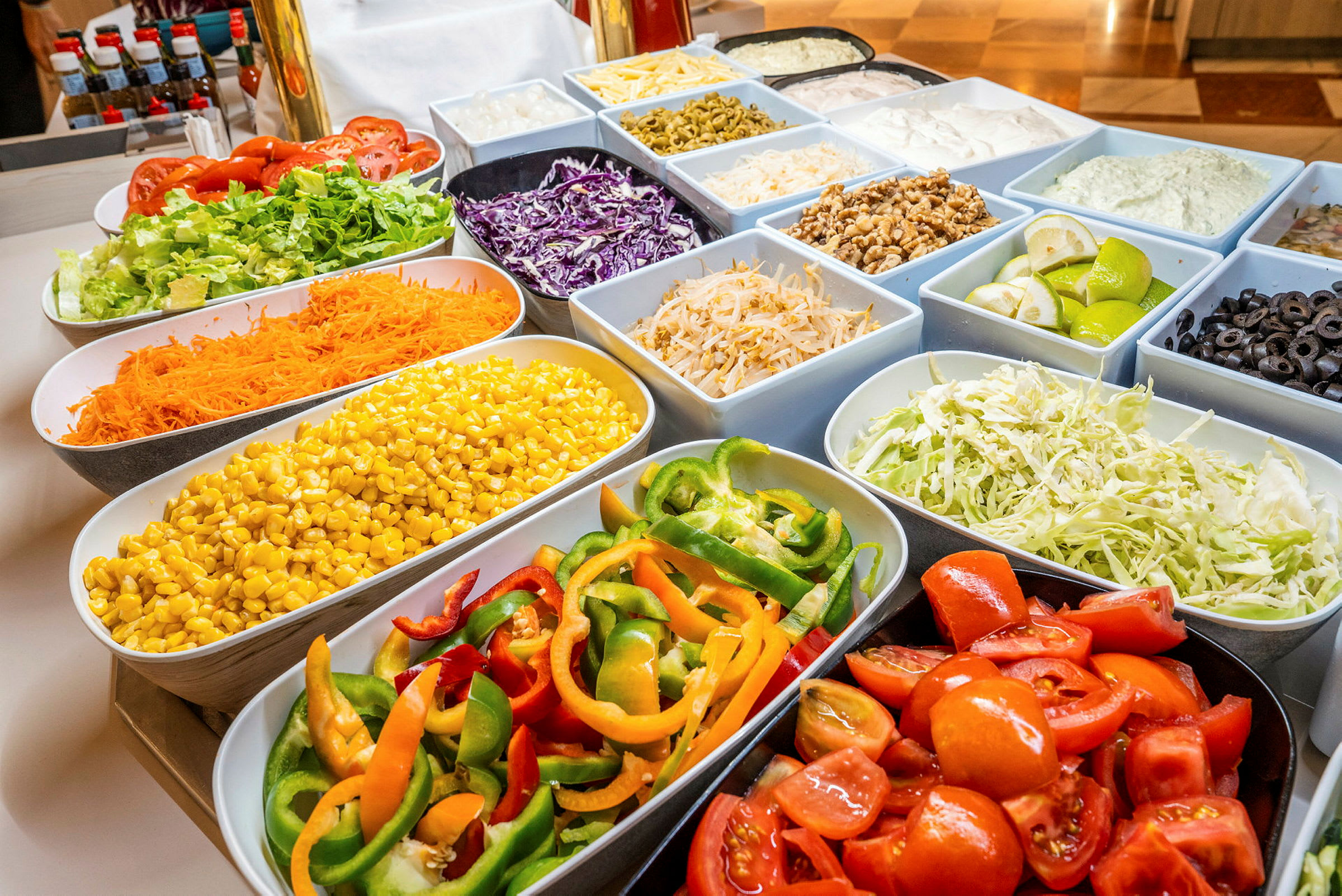 En buffé med ulike grønnsaker i boller, inkludert tomater, salat, mais, paprika og oliven. (AI-generert tekst)