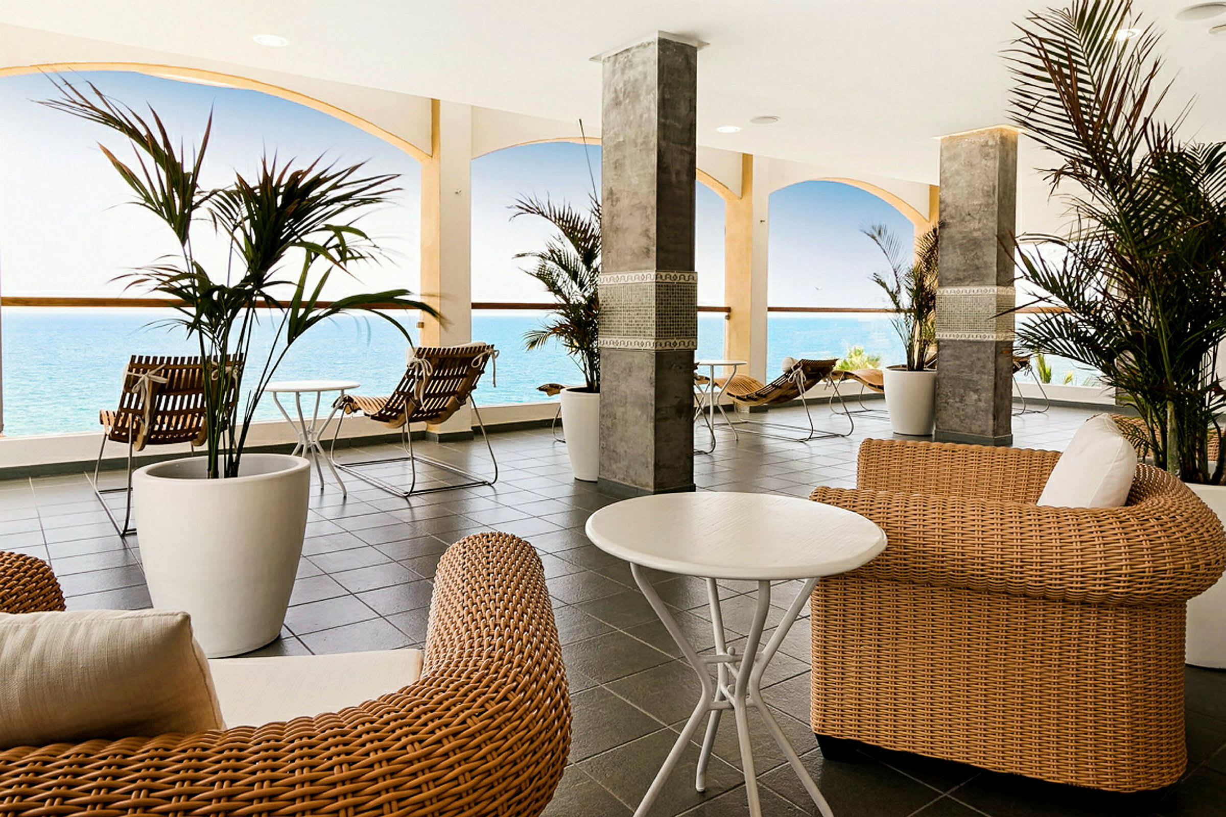 Sitteområde med rottingmøbler og havutsikt. (AI-generert tekst)