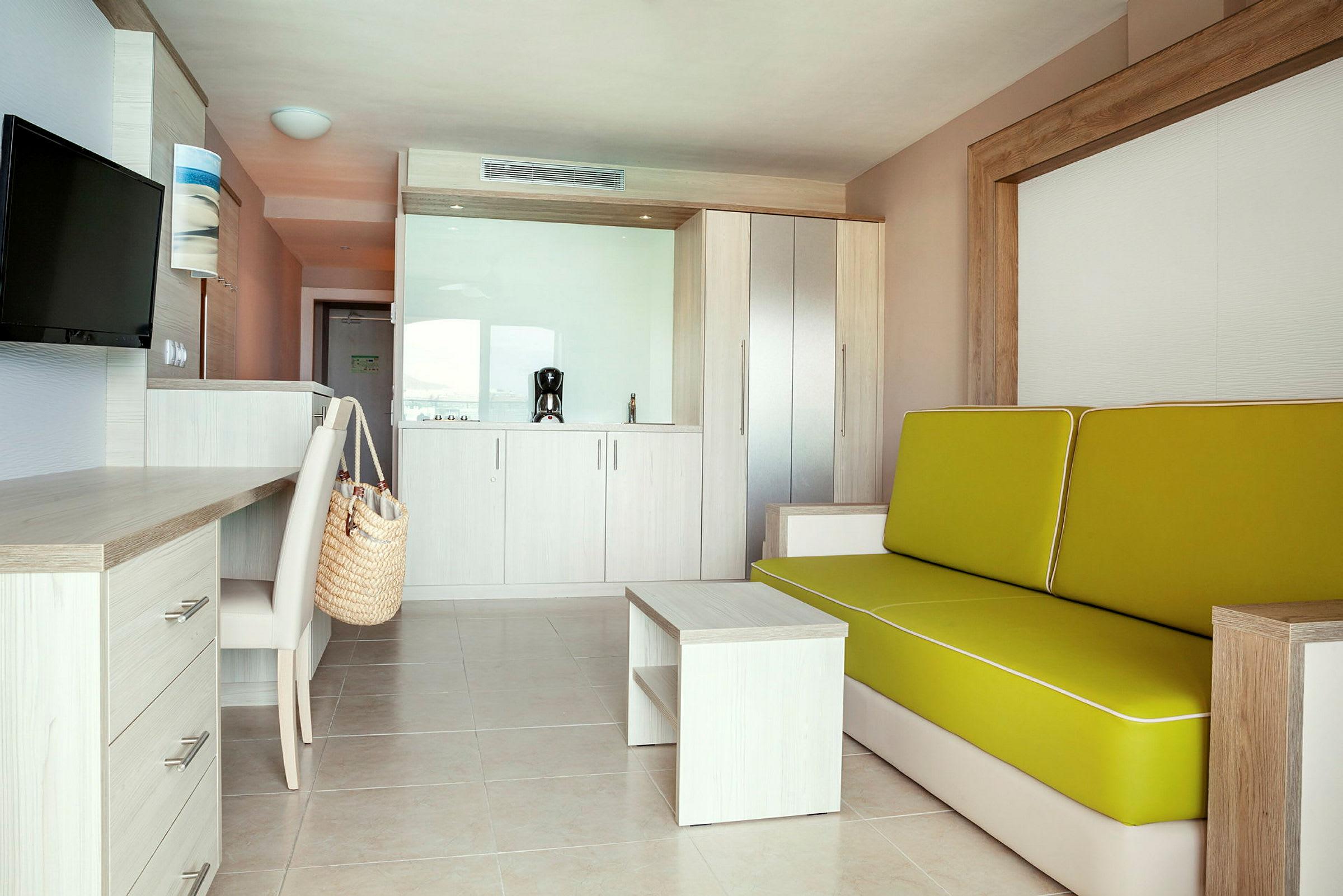 Moderne hotellrom med sofa, skrivebord og minikjøkken. (AI-generert tekst)