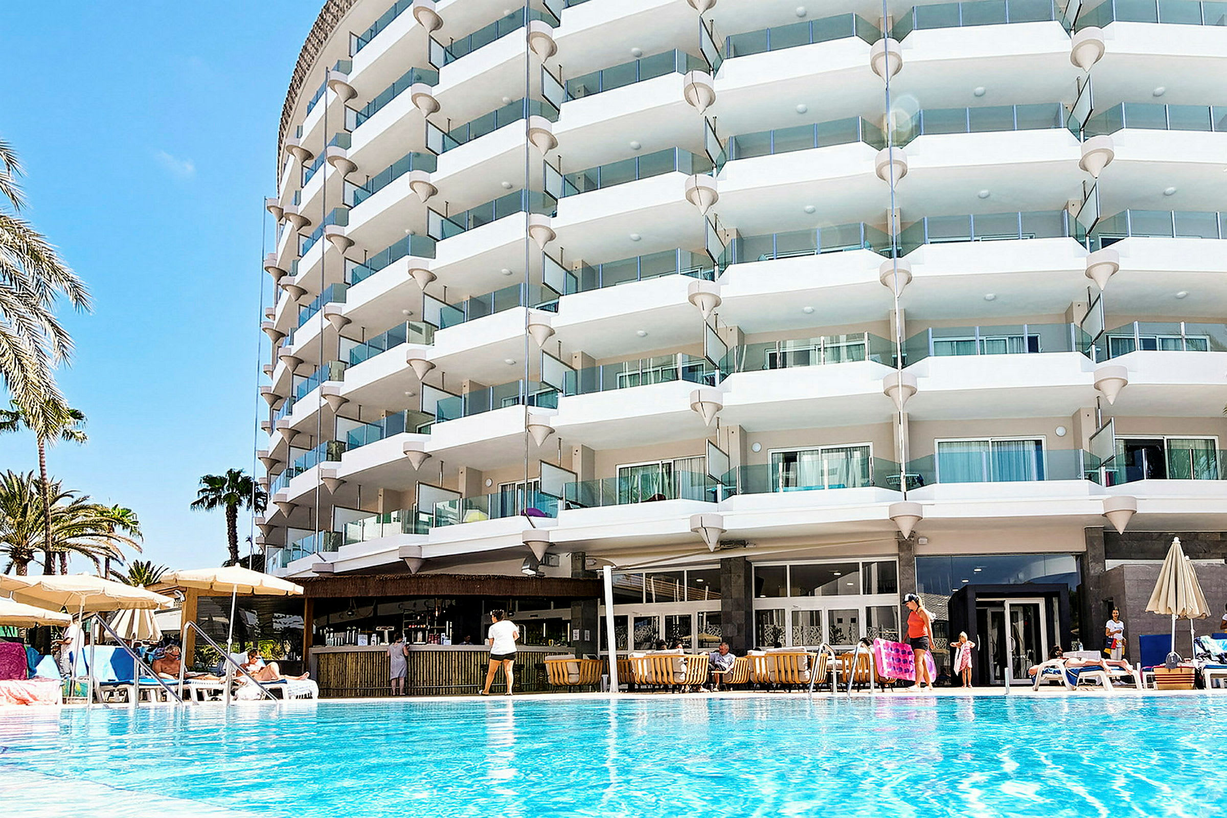 Et hotell med flere balkonger ved et basseng. (AI-generert tekst)