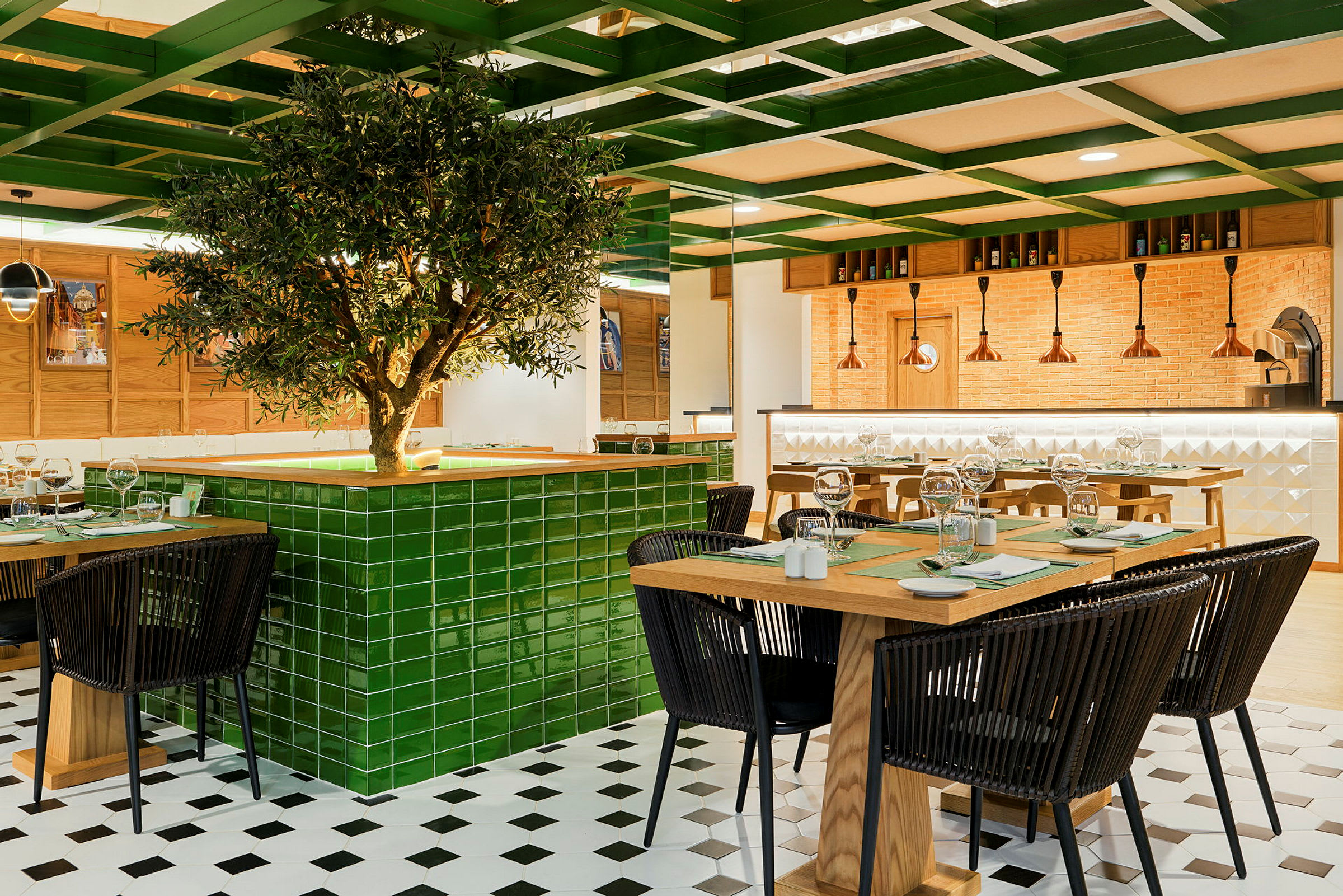 En moderne restaurant med trebord og svarte stoler, sentralt dekorert med et grønt tre med flislagt base. (AI-generert tekst)