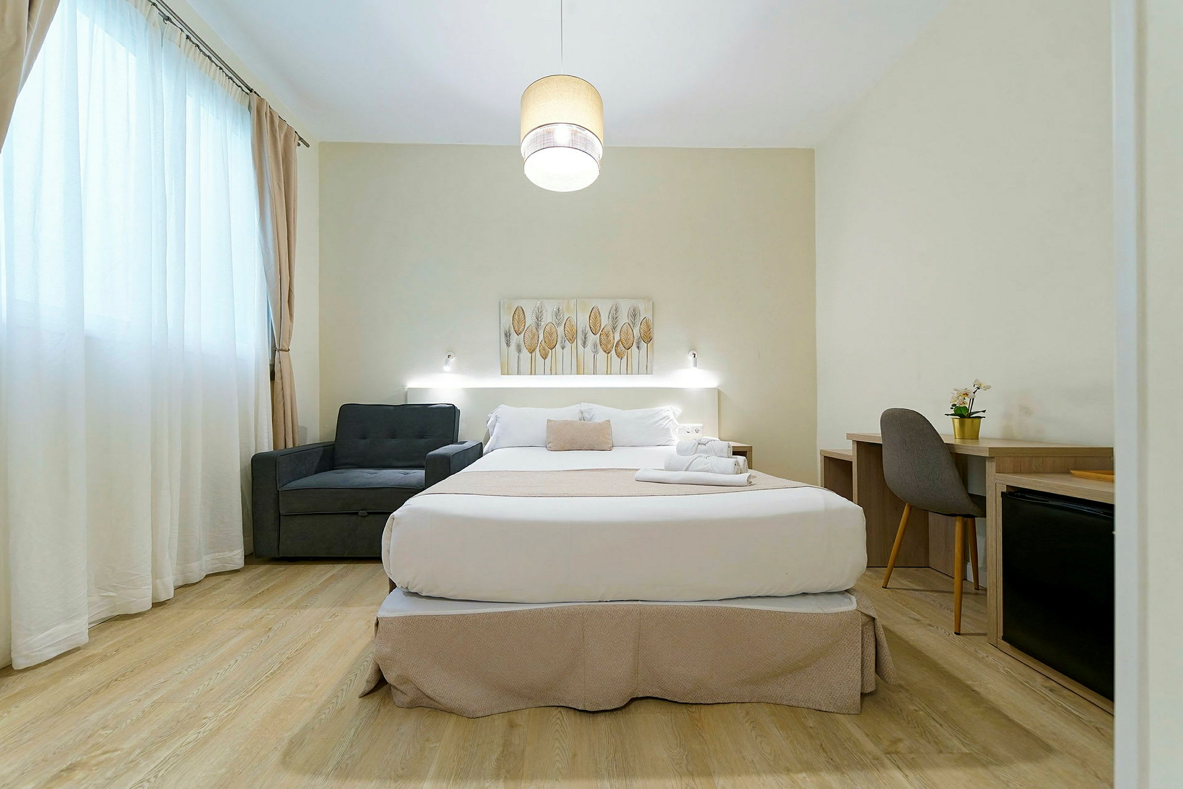 Et hotellrom med en dobbeltseng, lenestol og skrivebord. (AI-generert tekst)