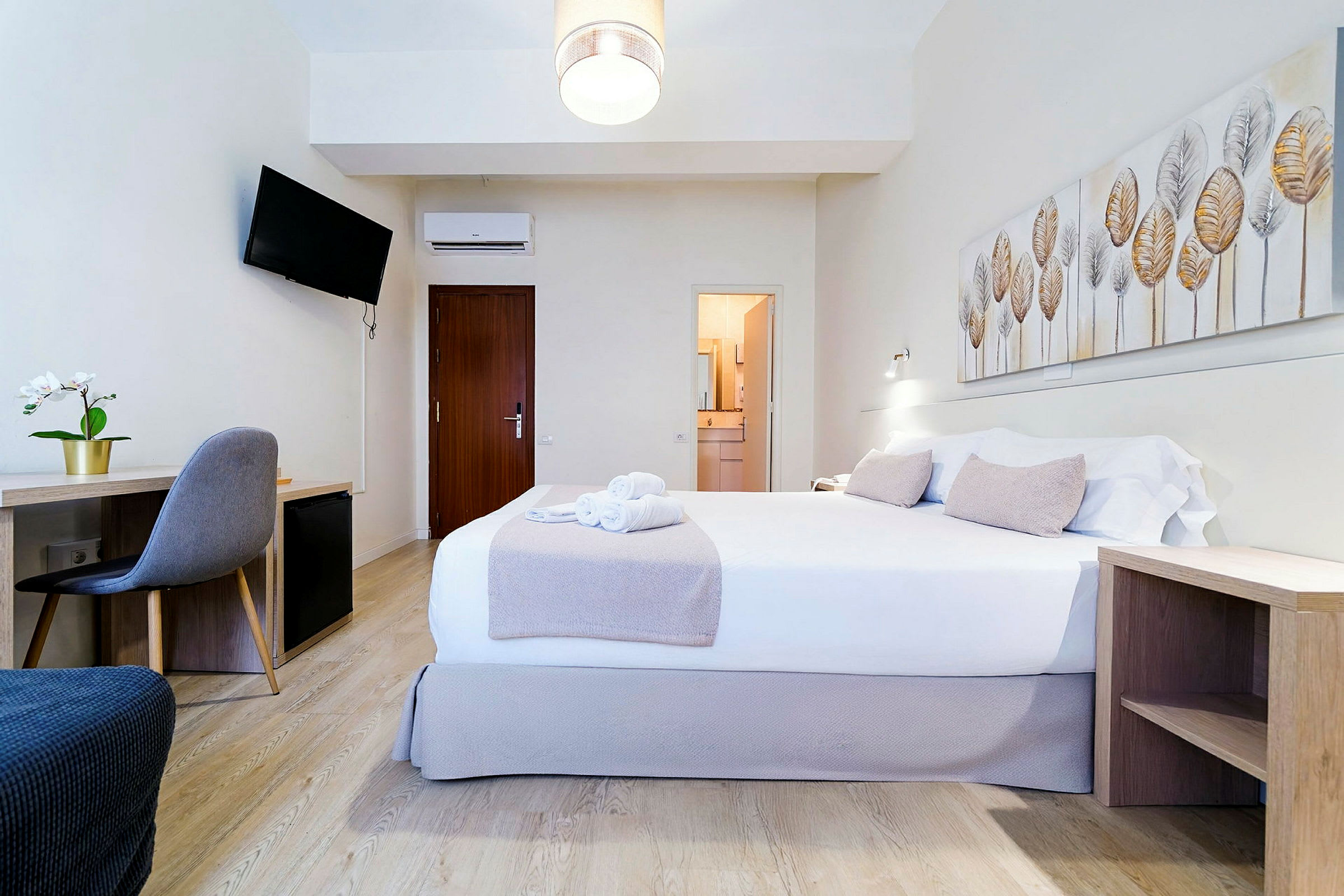 Et hotellrom med en dobbeltseng, skrivebord, stol og veggdekor. (AI-generert tekst)