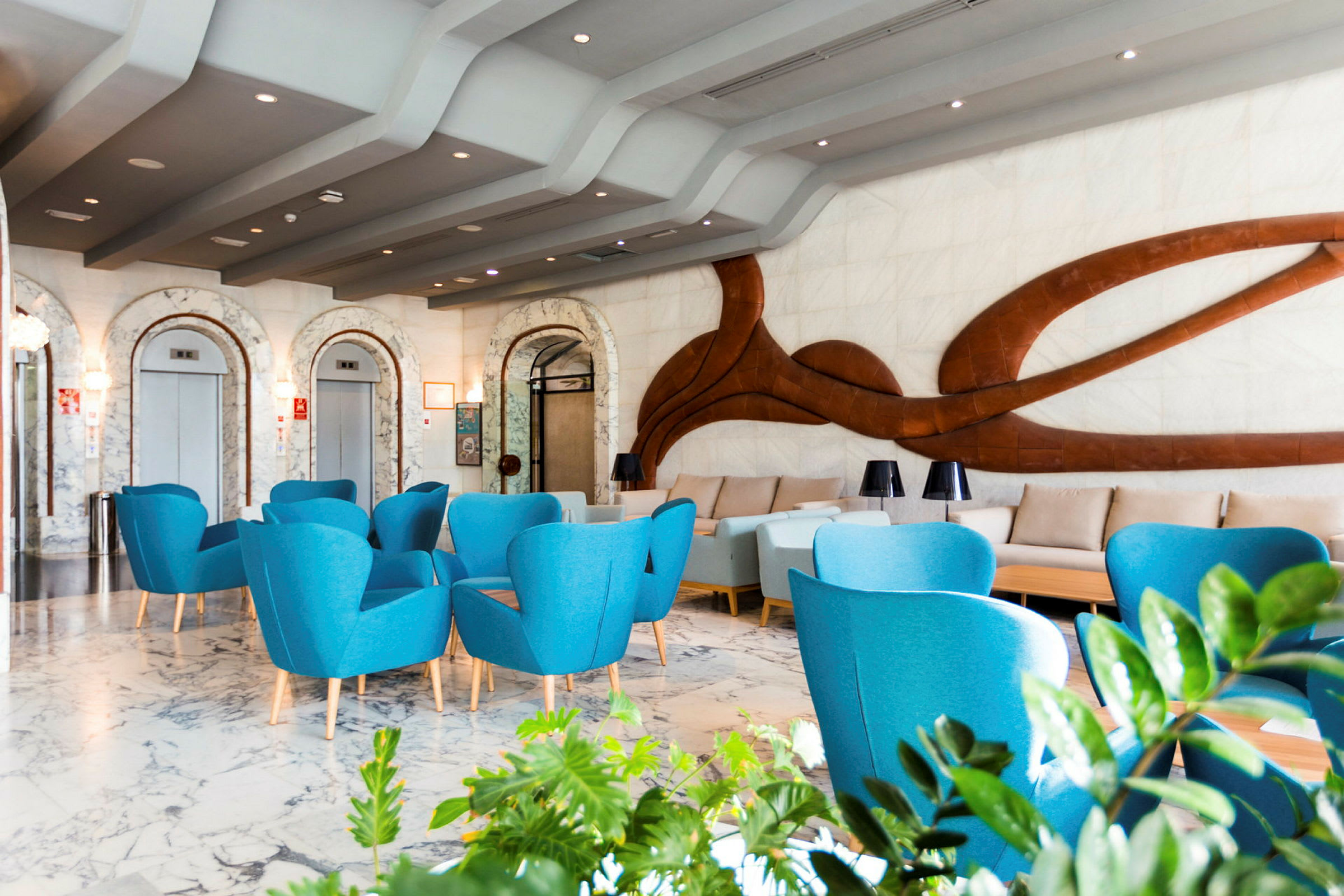 Moderne hotellobby med blå lenestoler og dekorativ vegg. (AI-generert tekst)