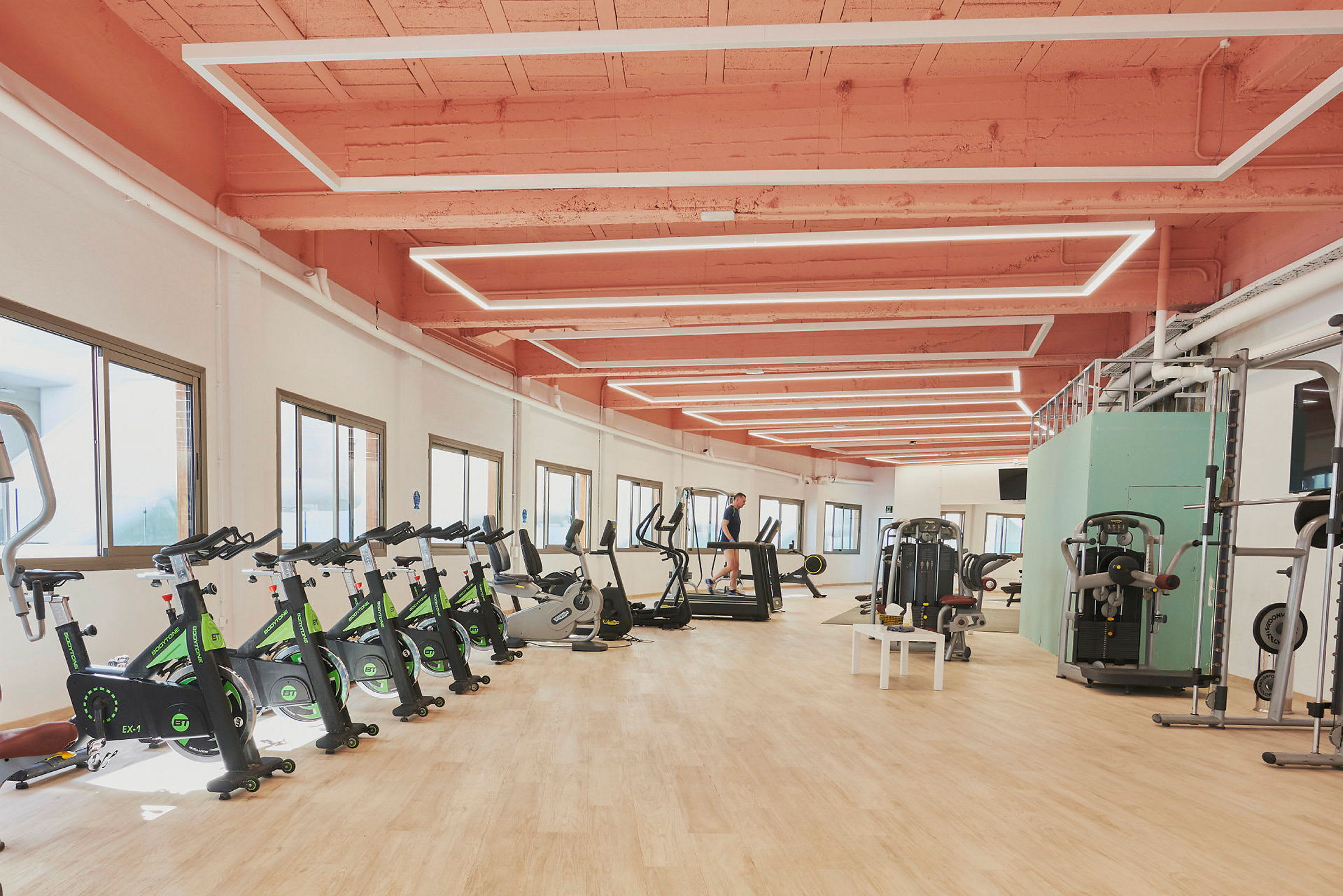 Et treningsstudio med treningsutstyr, inkludert treningssykler, tredemøller og styrketreningsmaskiner. (AI-generert tekst)