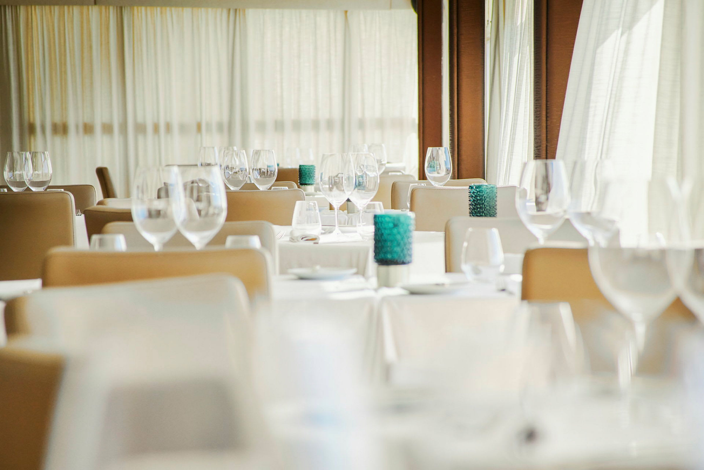 Et elegant restaurantområde med dekkede bord, sitteplasser og dekorative glass. (AI-generert tekst)