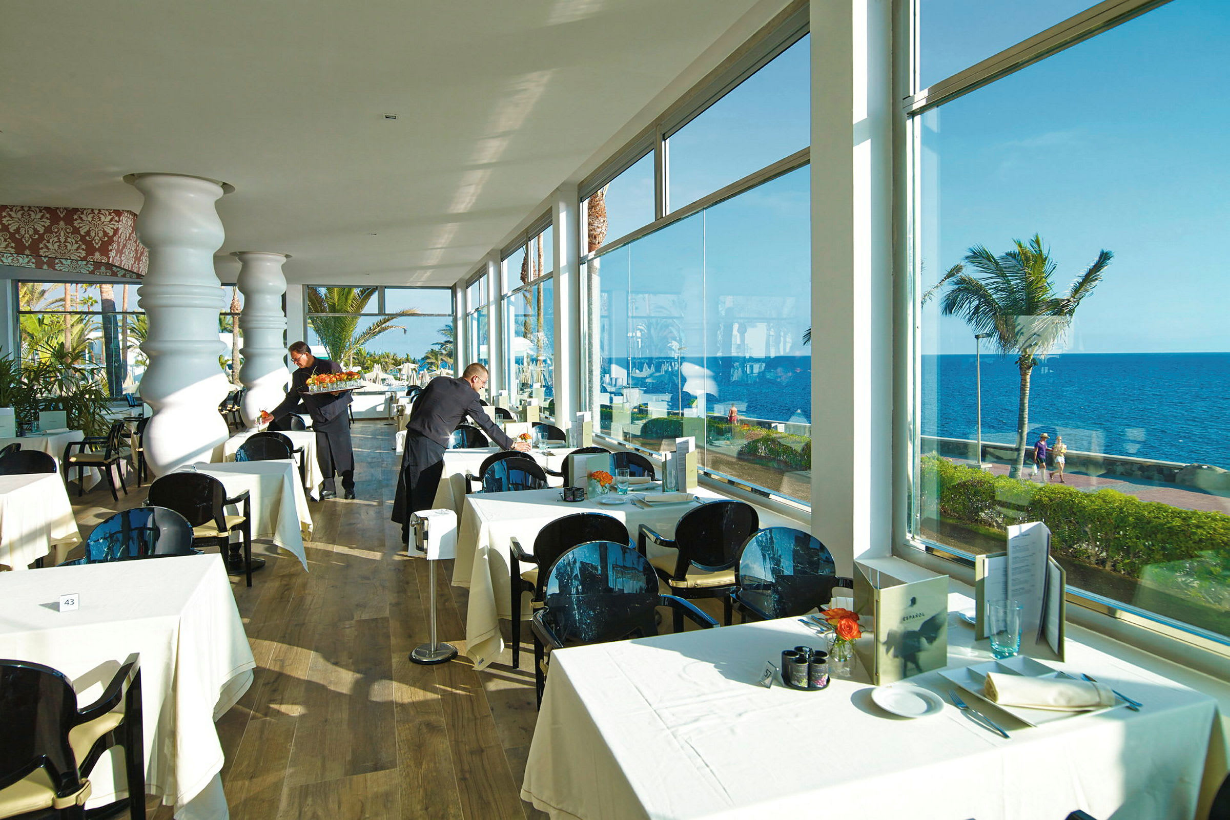 Restaurant med oppdekkede bord nær vinduer med havutsikt. (AI-generert tekst)