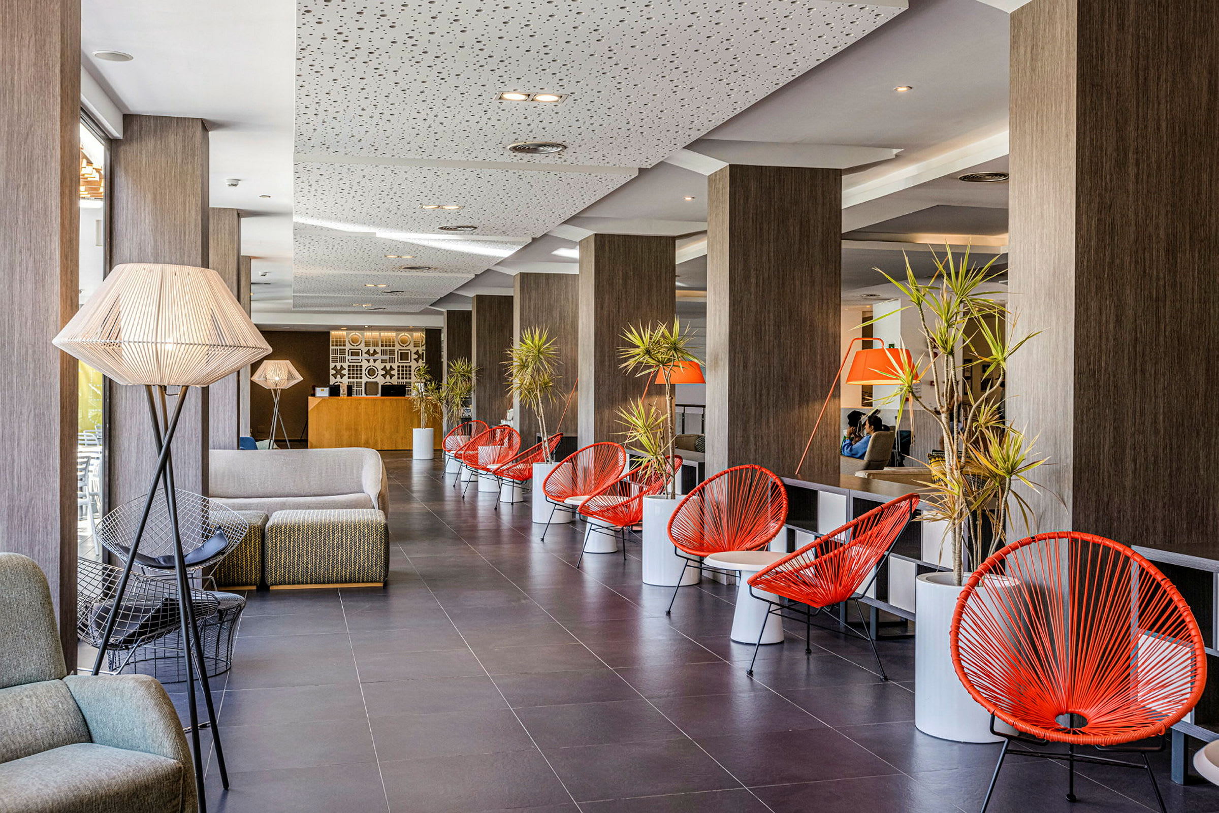 Hotellobby med sittegrupper og røde stoler. (AI-generert tekst)