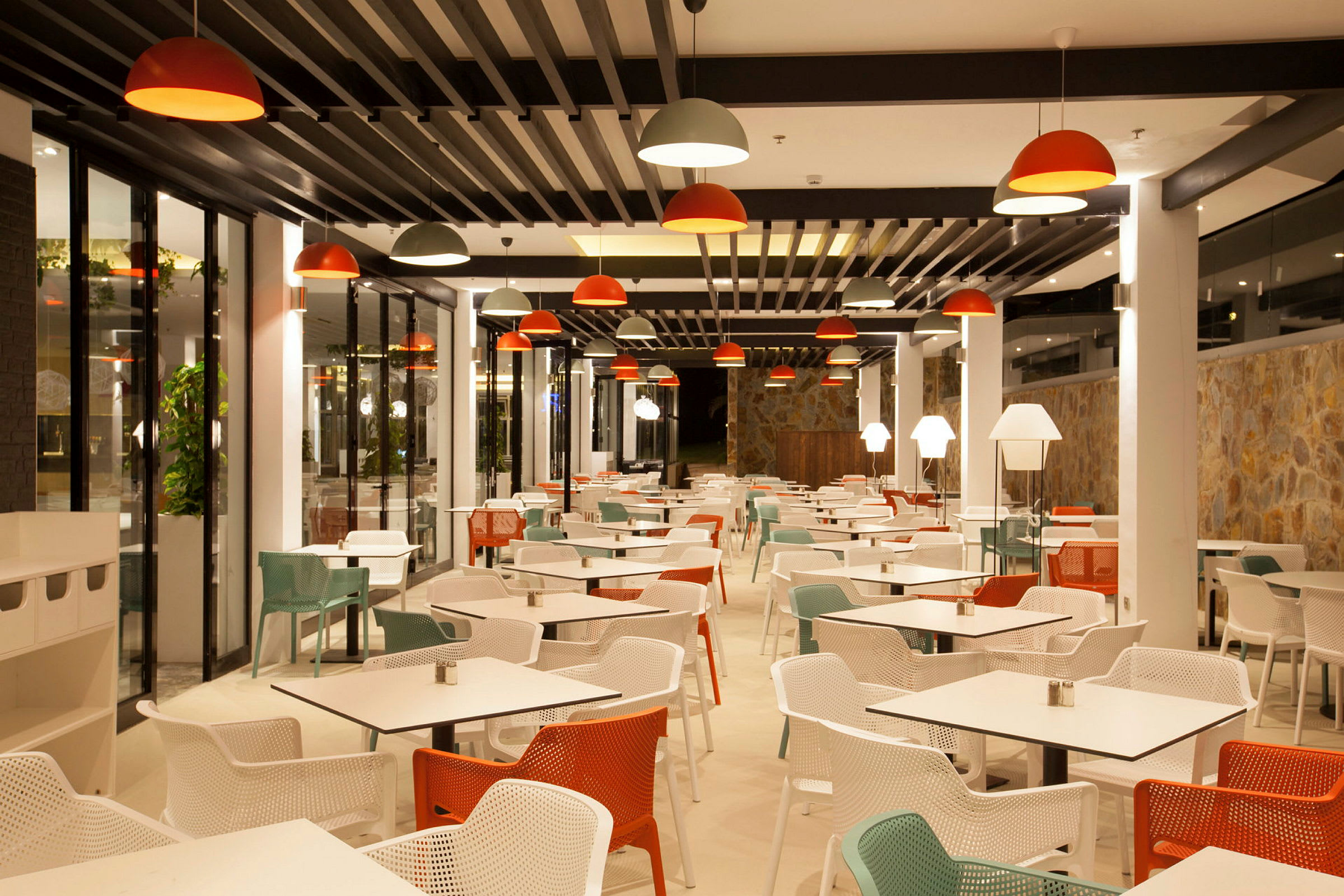 Interiør av en moderne restaurant med sitteplasser. Belysning med rødt og hvitt. (AI-generert tekst)