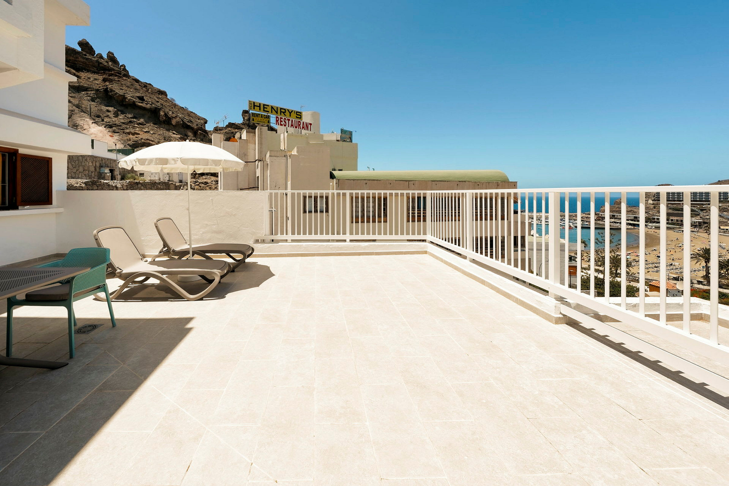 Terrasse med solsenger, paraply og utsikt over havet. (AI-generert tekst)