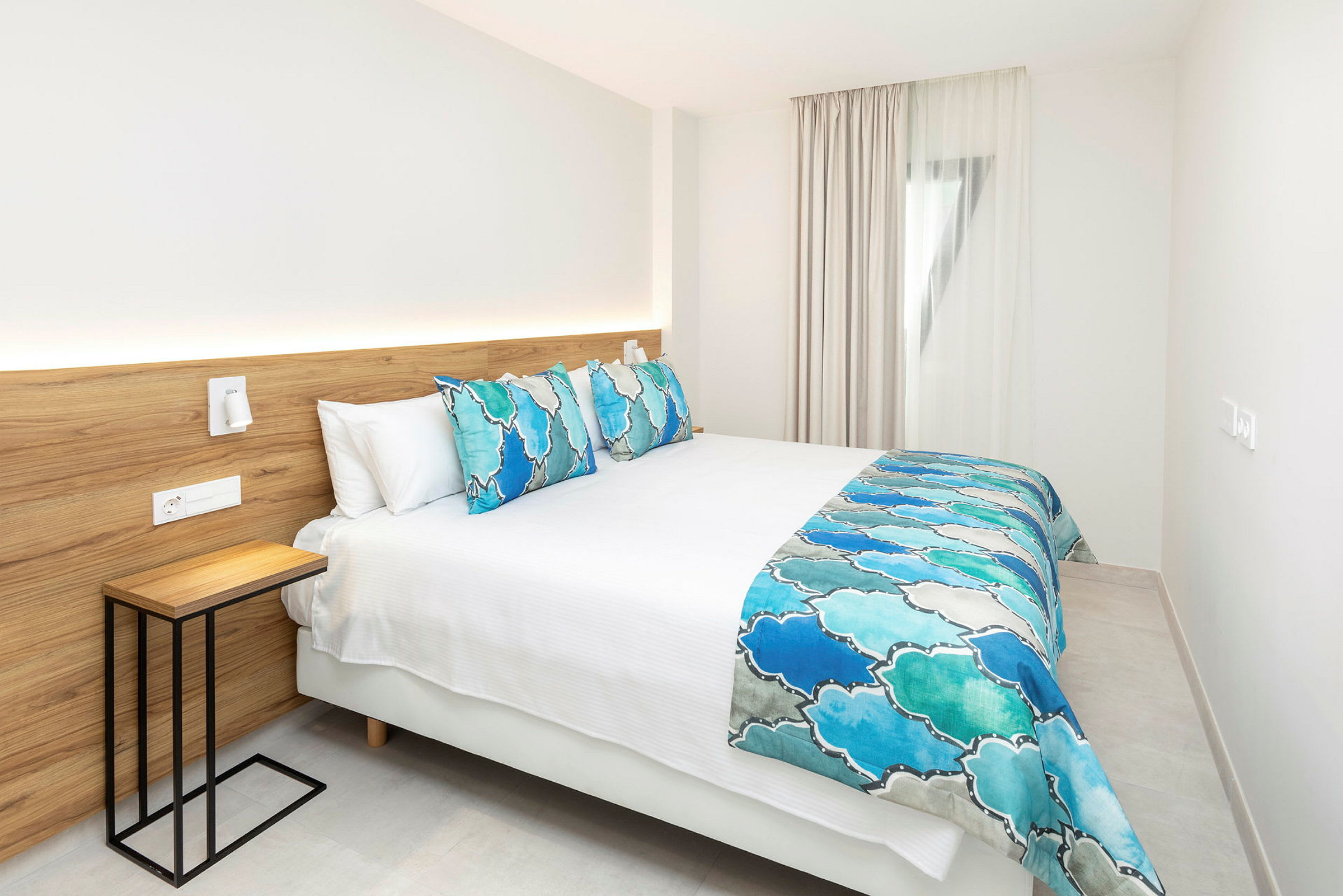 Moderne hotellrom med en dobbeltseng med blå og hvite sengetepper. (AI-generert tekst)