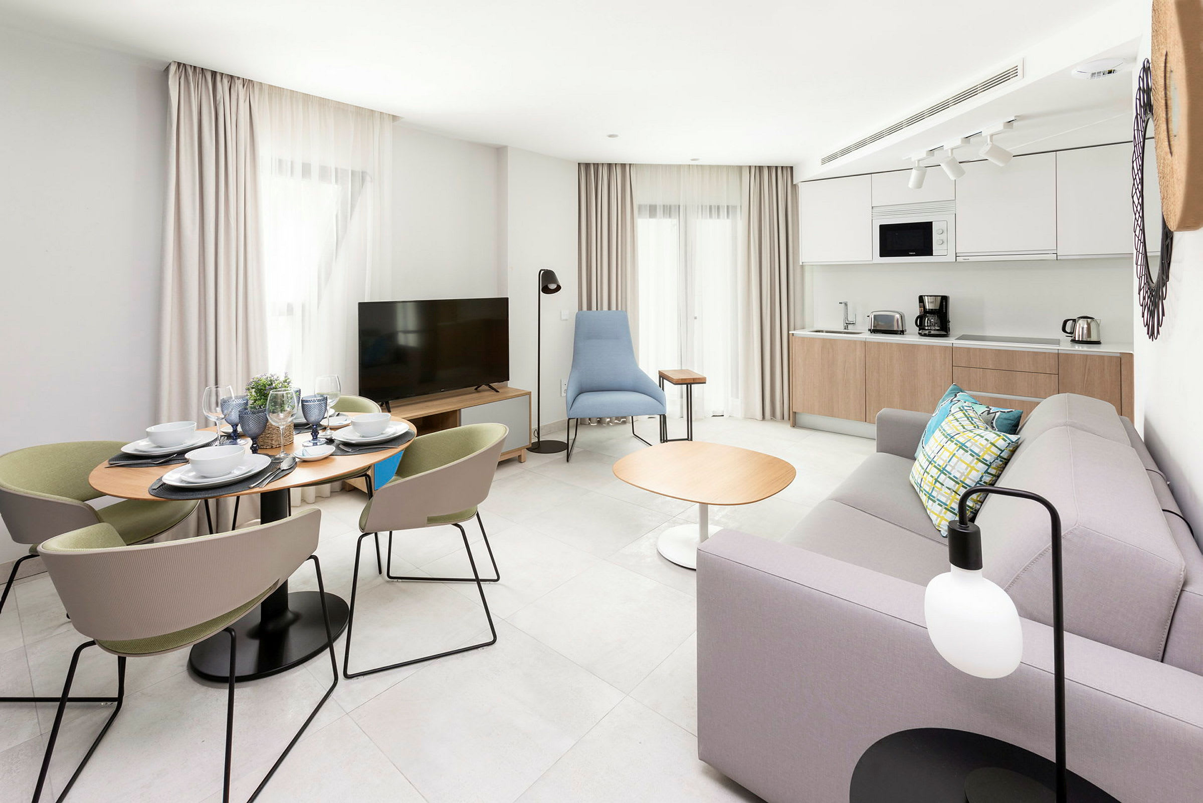 Et moderne oppholdsrom med spisebord, sofa, TV og kjøkken. (AI-generert tekst)