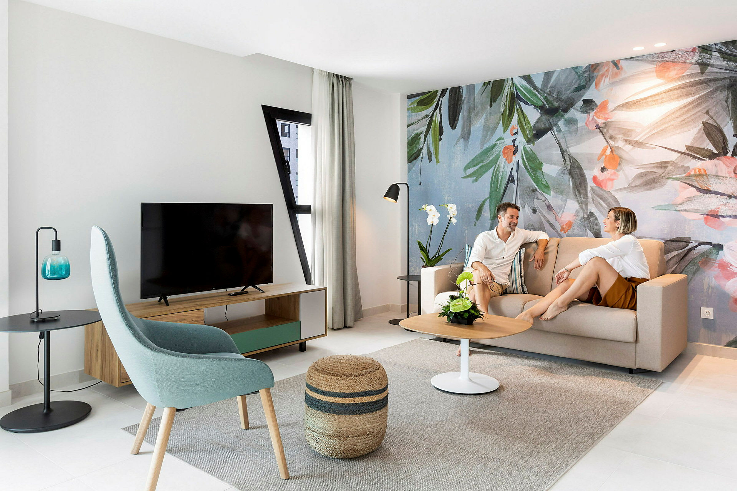 En moderne stue med sofa, bord og veggdekorasjon med botanisk tema. (AI-generert tekst)