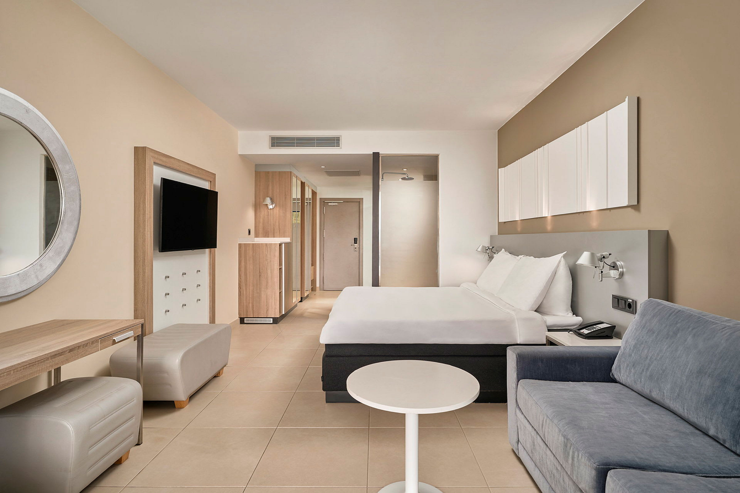 Hotellrom med en dobbeltseng, sofa og skrivebord. (AI-generert tekst)