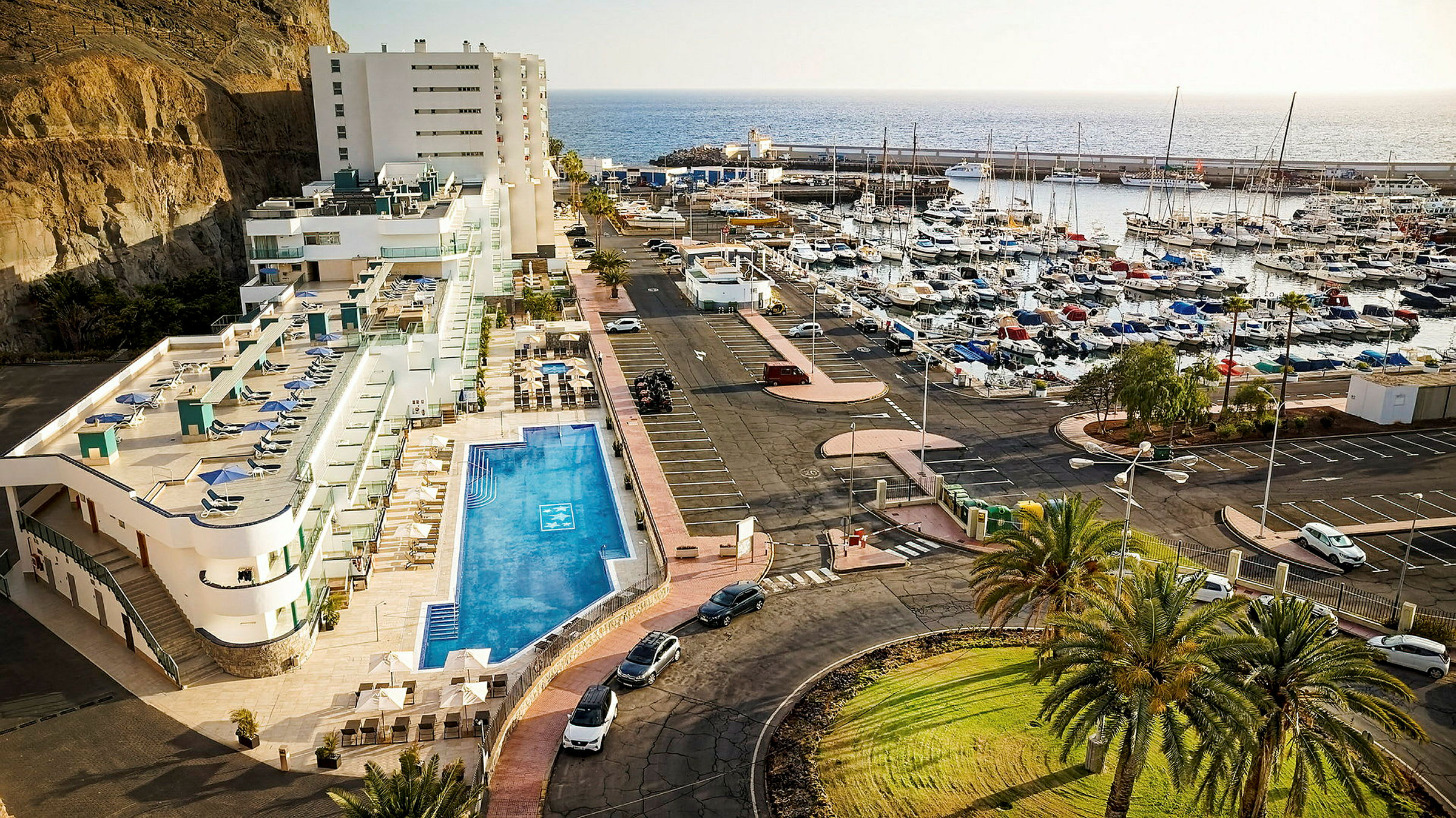 Hotellets bassengområde og marina med båter ved kysten. (AI-generert tekst)