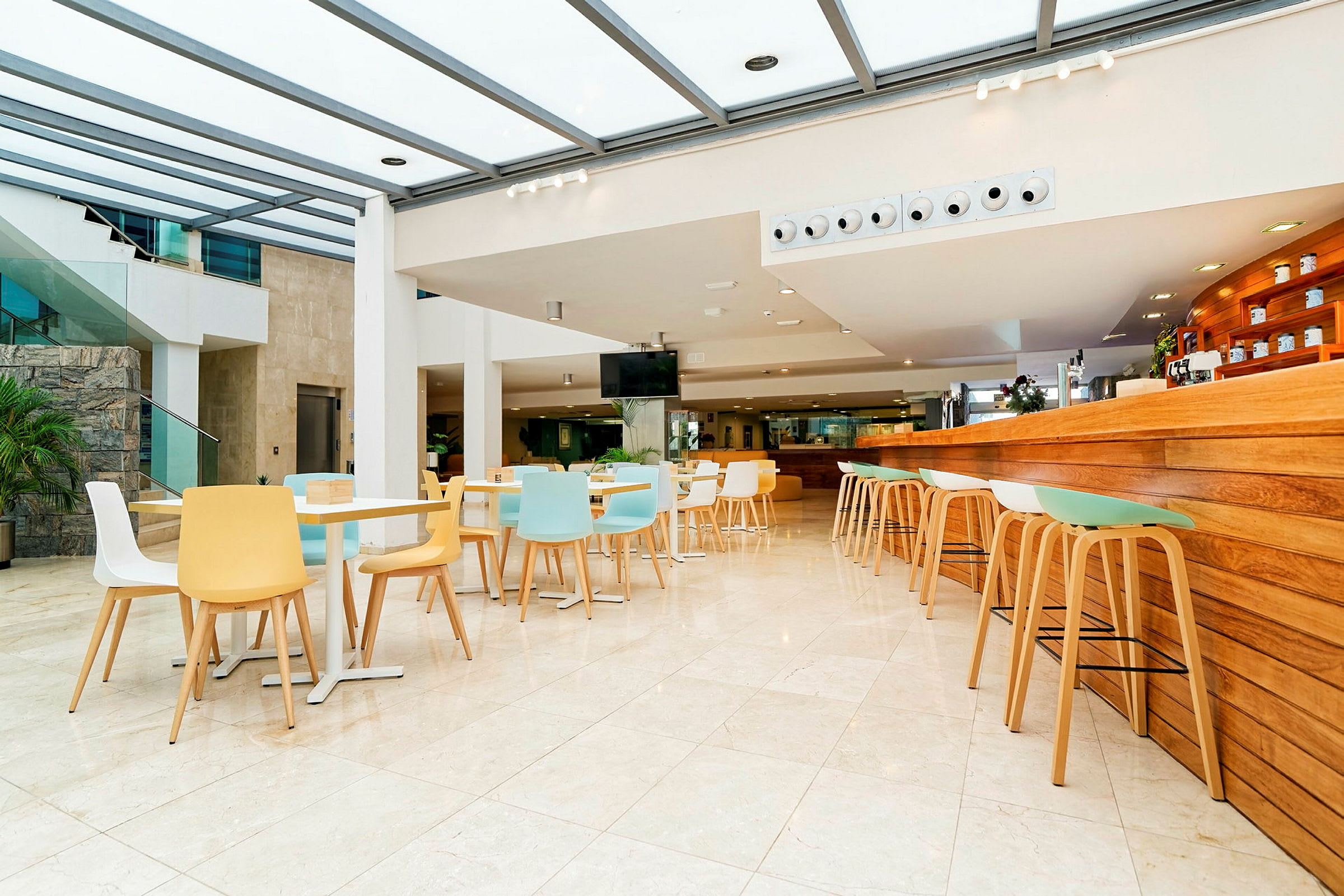 Lyst og moderne kafé med fargerike stoler og et serveringsområde med trepanel. (AI-generert tekst)