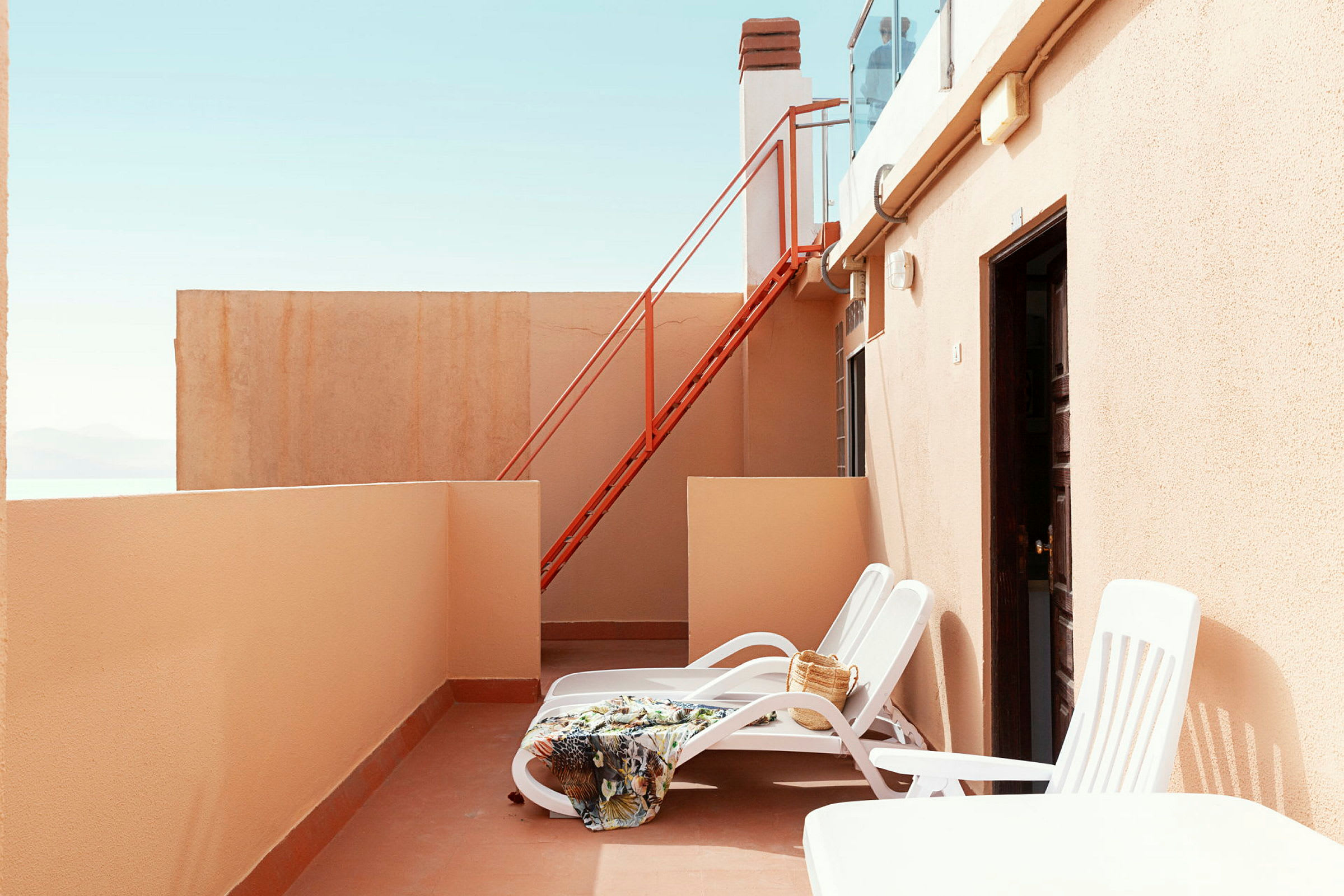 Privat terrasse med solsenger, teppe og veske. (AI-generert tekst)