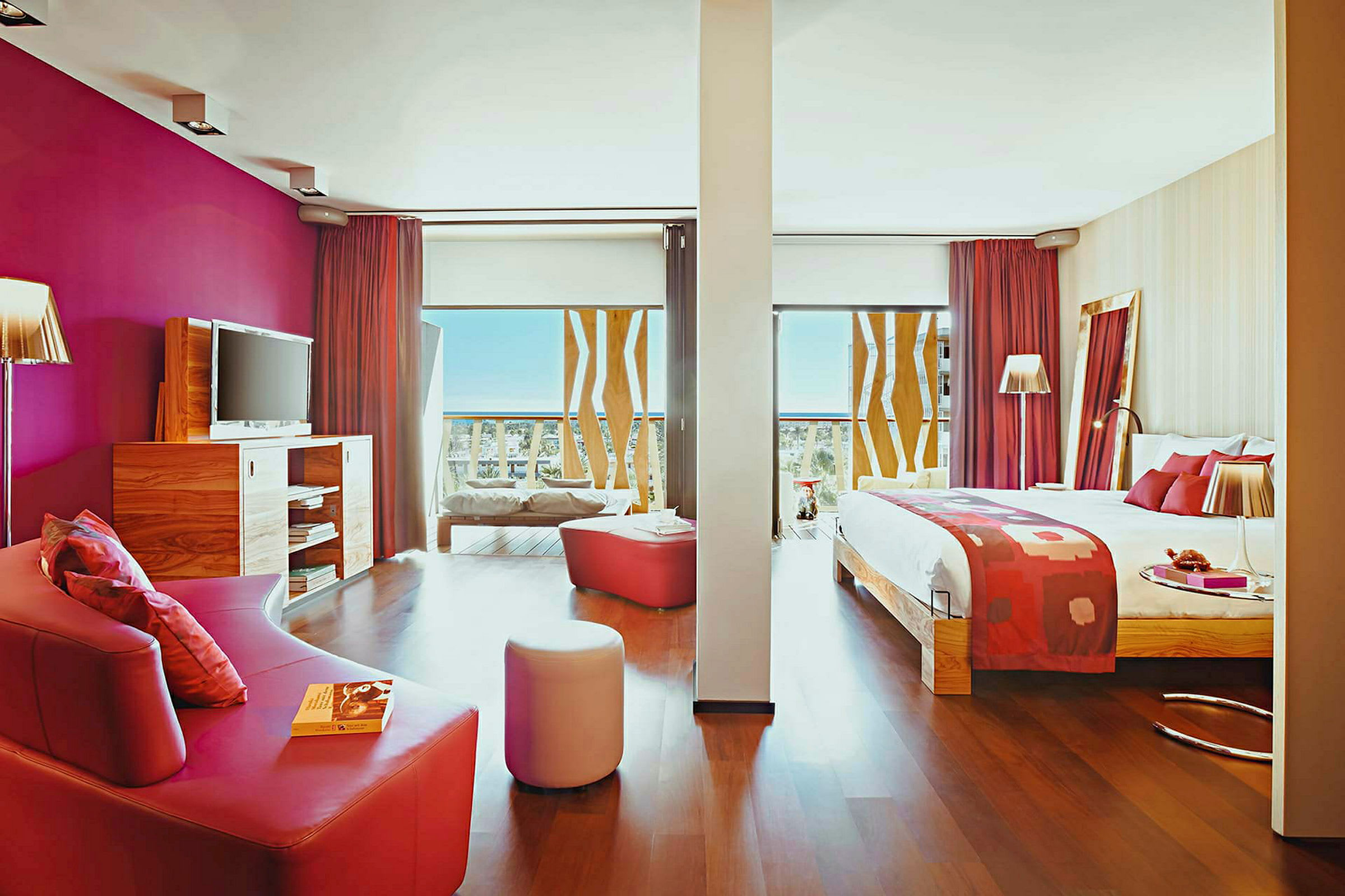 Hotellrom med seng, sofa og moderne interiør med rosa detaljer. (AI-generert tekst)