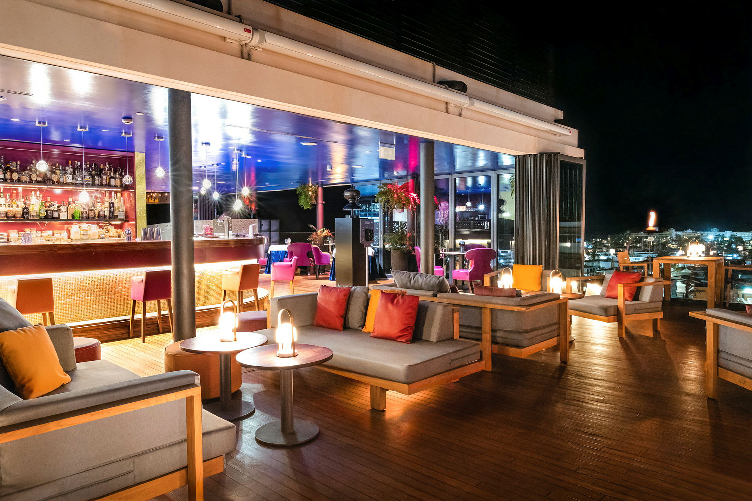 En takterrassebar med sitteplasser og belysning om natten. (AI-generert tekst)