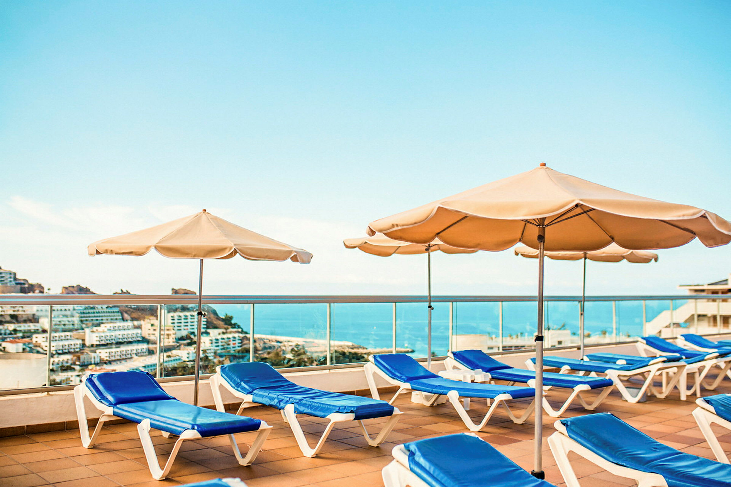 Solstoler og parasoller på en terrasse med utsikt over havet. (AI-generert tekst)