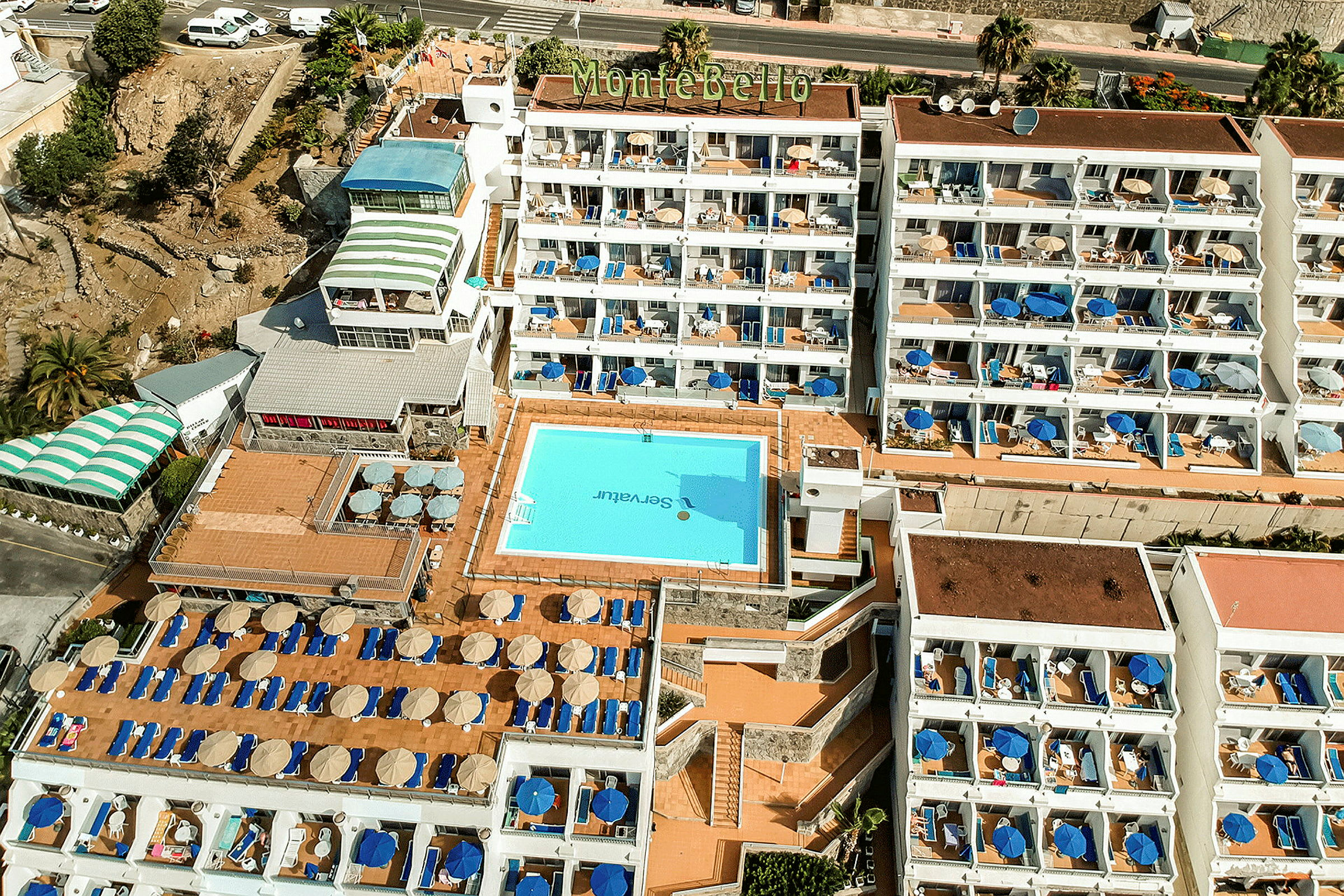 Flyfoto av hotell Montebello med basseng og solsenger. (AI-generert tekst)