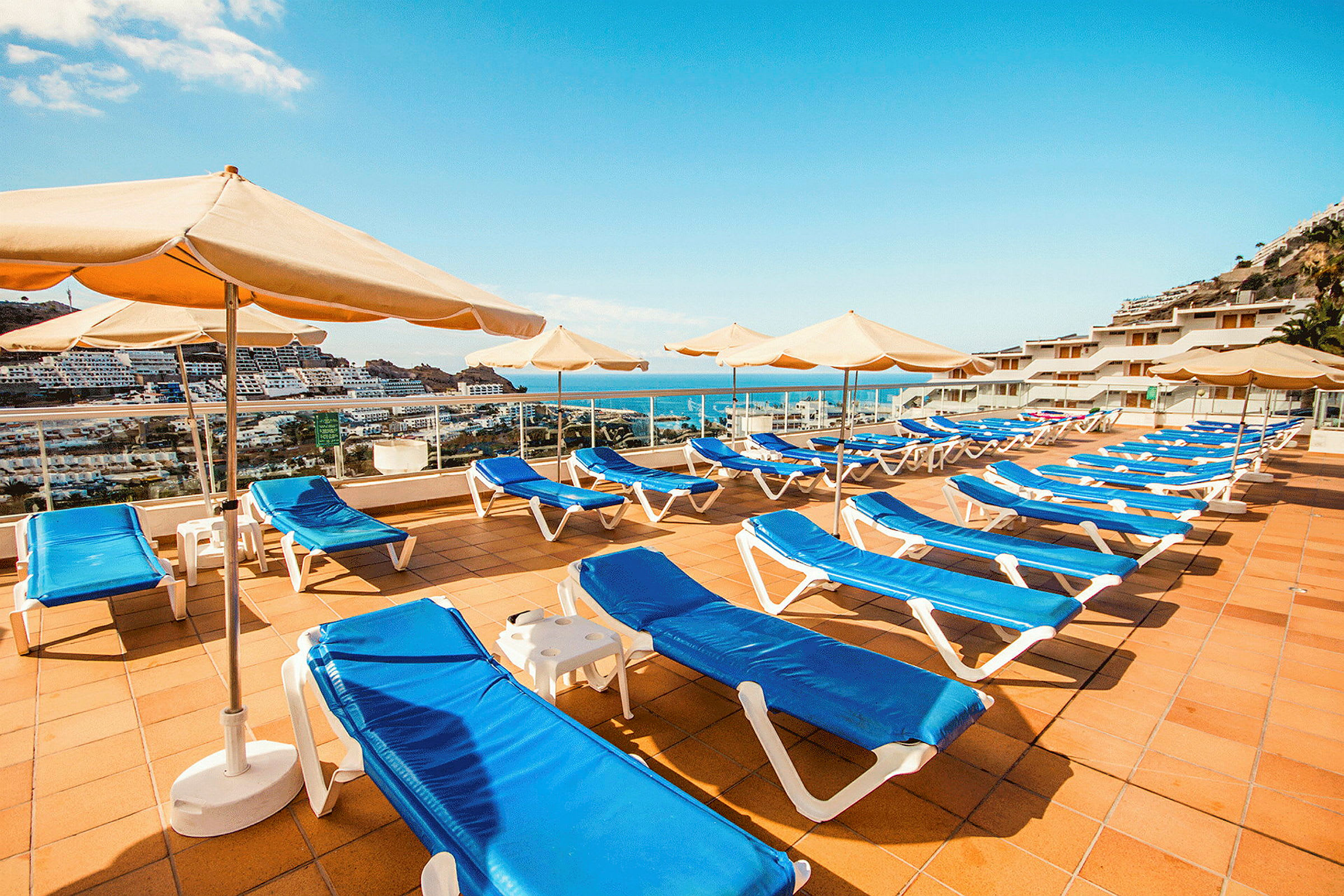 Solstoler og parasoller på en solterrasse med havutsikt. (AI-generert tekst)