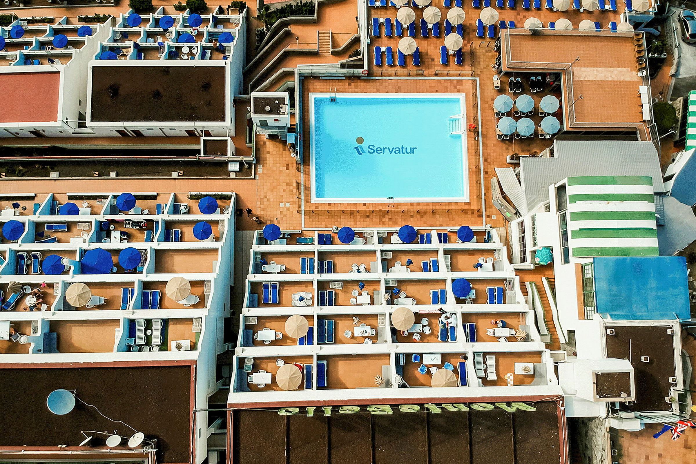 Luftfoto av hotellområde med basseng og terrasser. (AI-generert tekst)