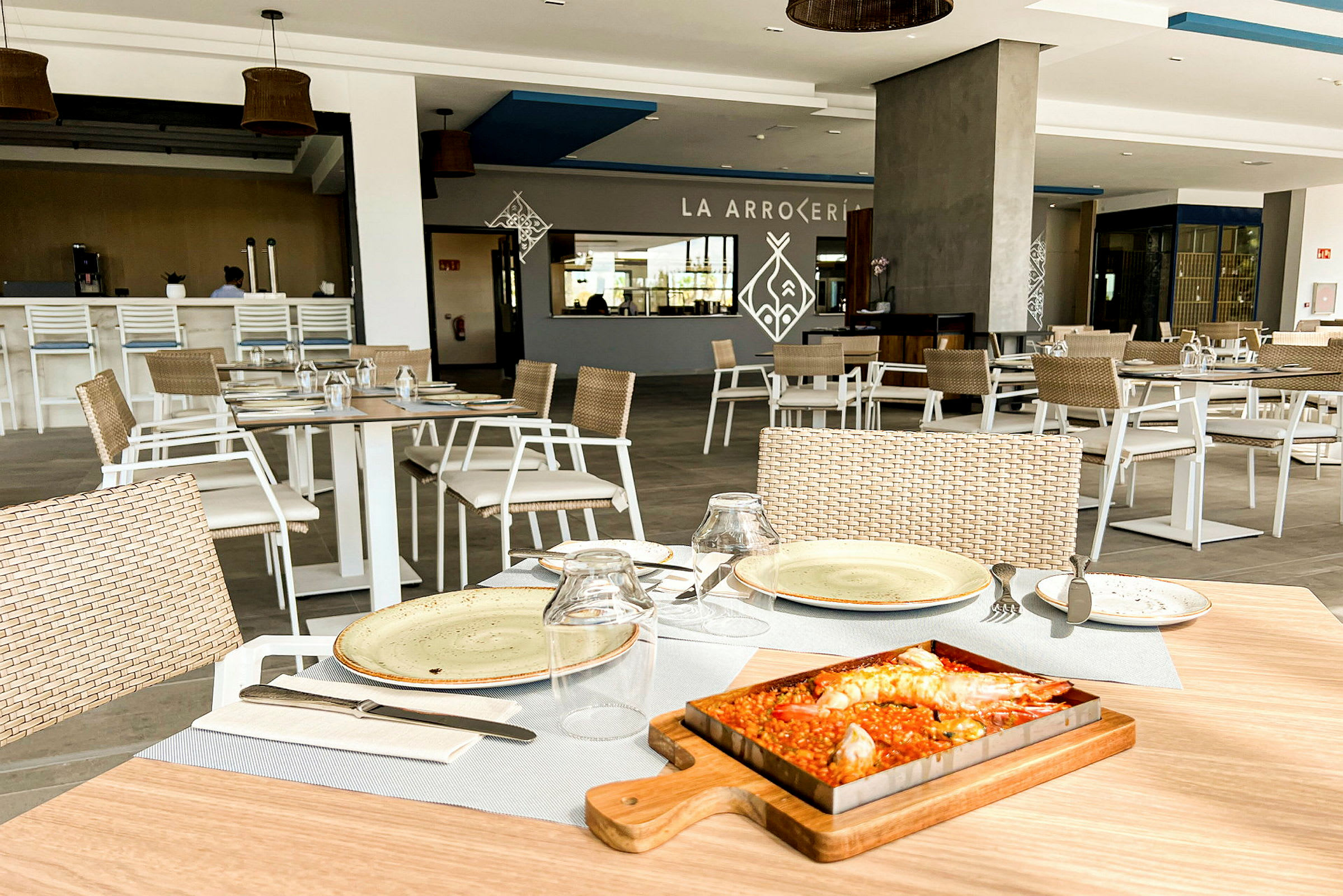Bilde av en restaurant med dekkede bord og servert rett, en paella. (AI-generert tekst)