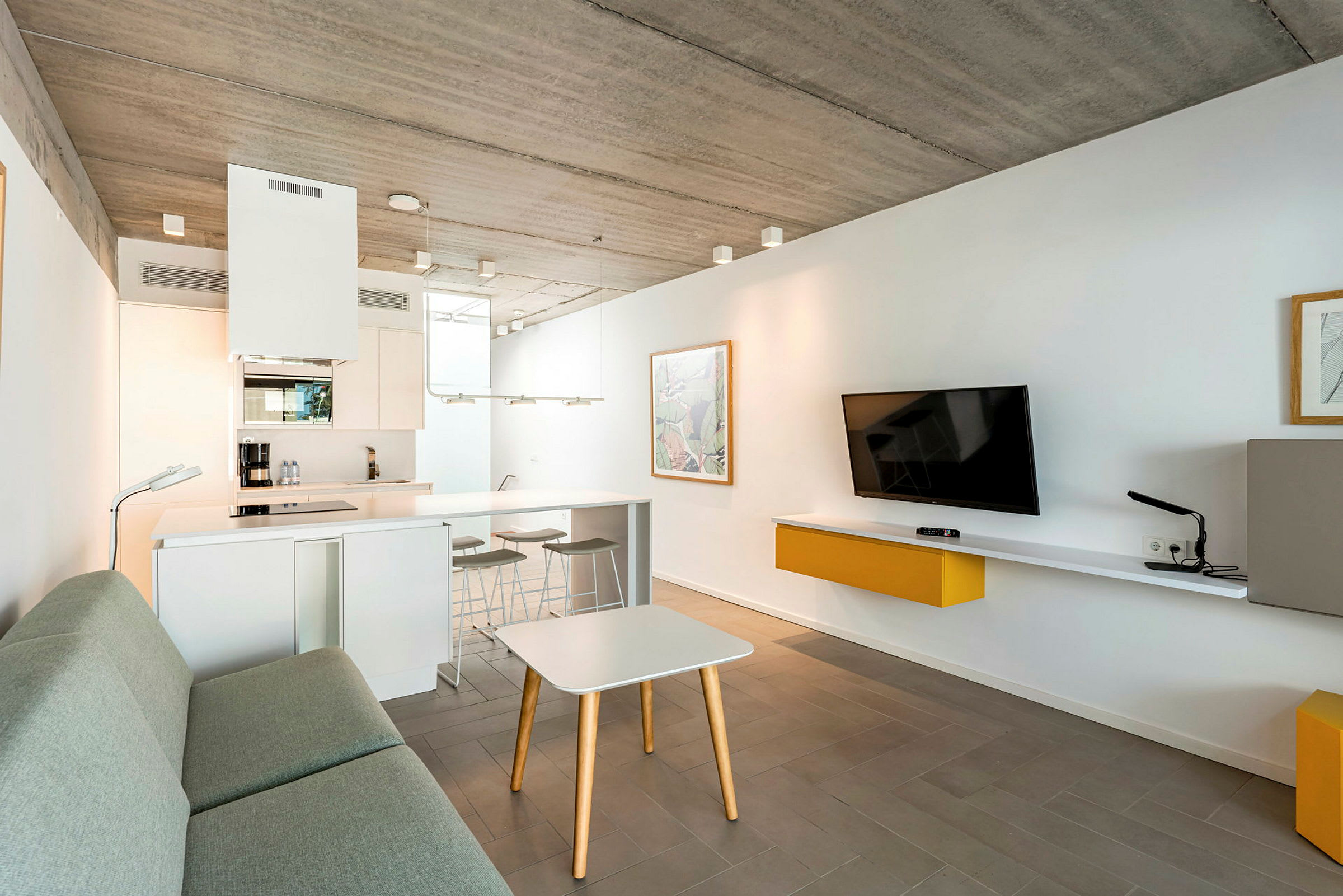 En moderne, minimalistisk stue med kjøkkenområde og grå sofa. (AI-generert tekst)