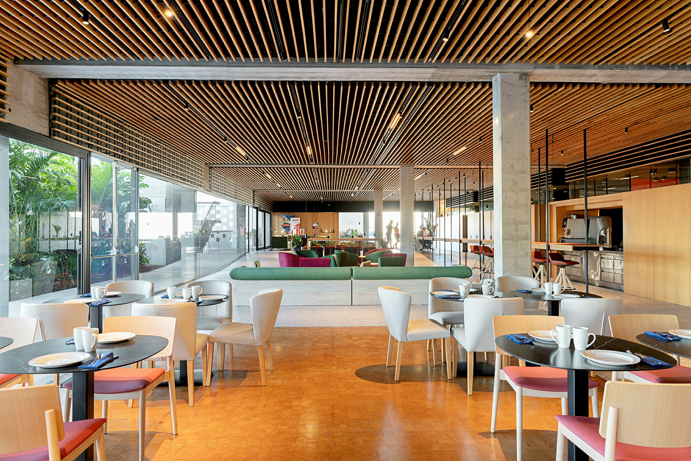 En moderne lounge med bord og stoler, sofaer og et glasstak. (AI-generert tekst)