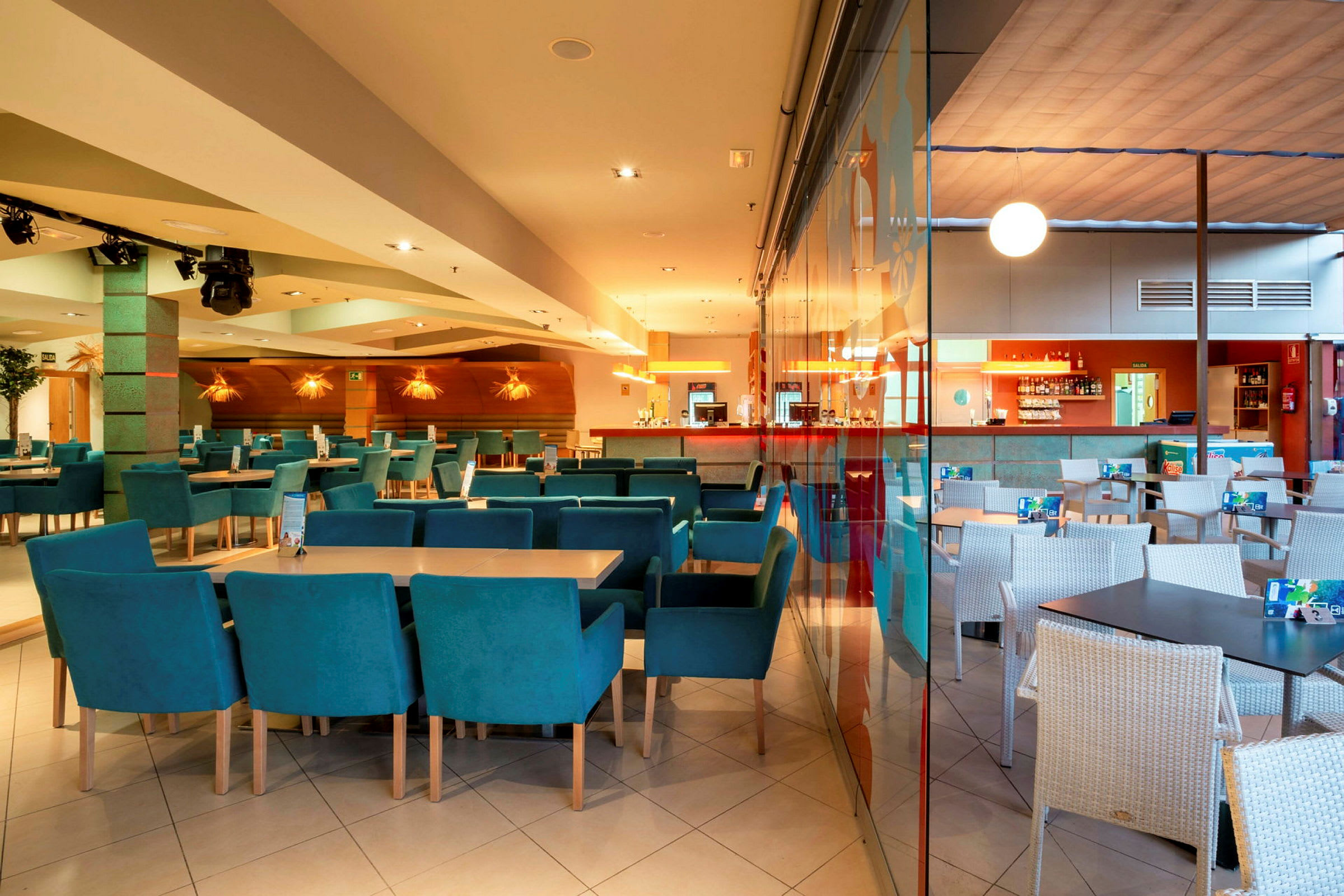 Interiør av en restaurant med bord og stoler, samt en bardisk i bakgrunnen. (AI-generert tekst)