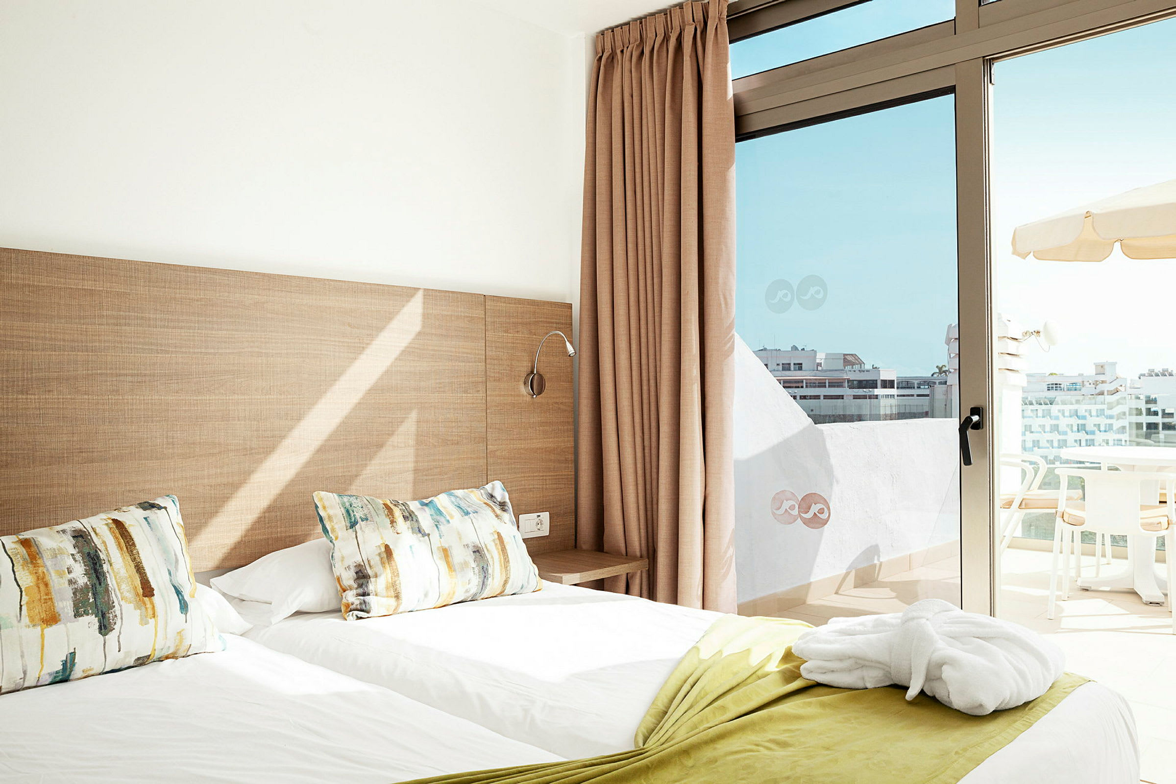 Hotellrom med to enkeltsenger og en balkong med utsikt. (AI-generert tekst)