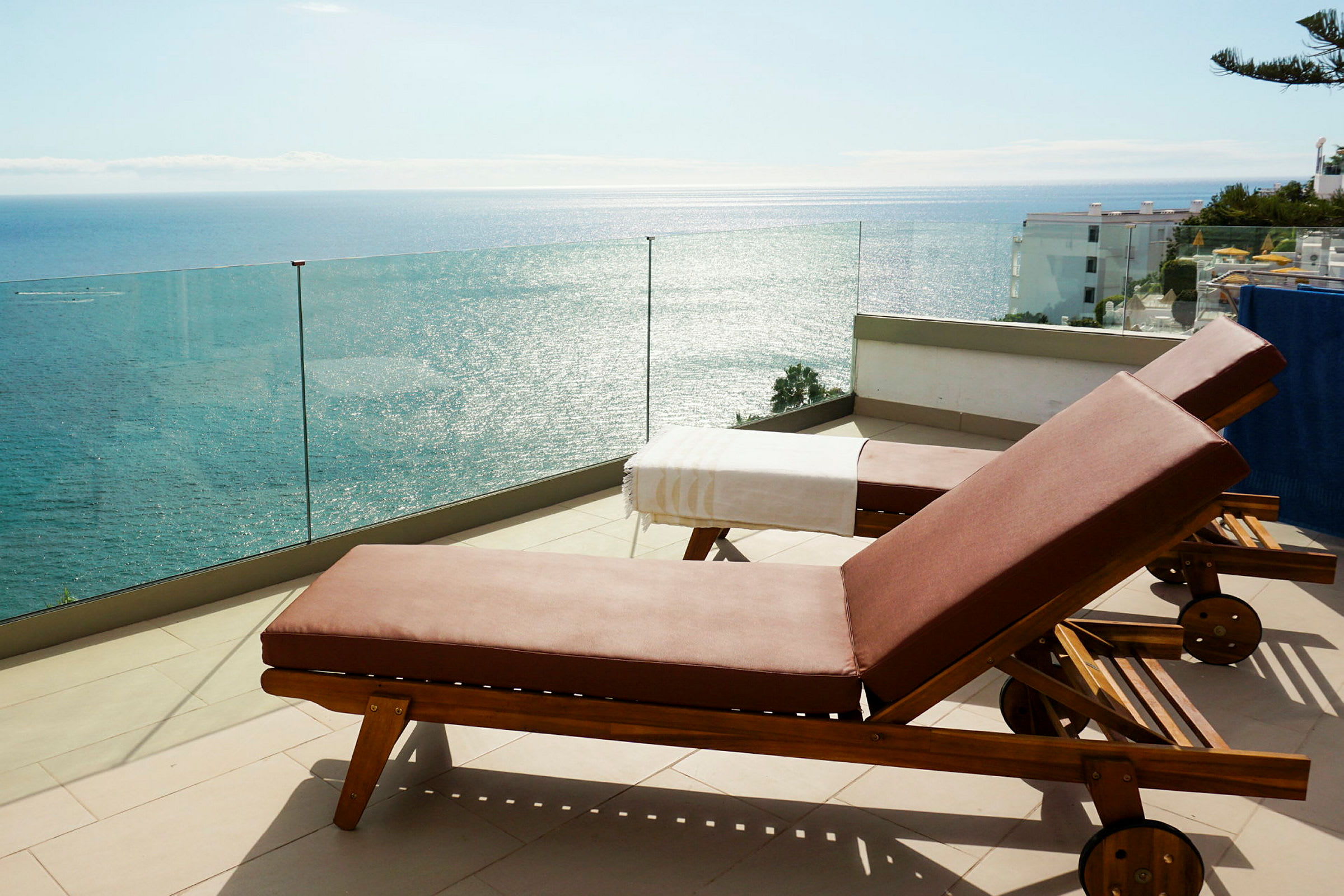 To solsenger på en terrasse med utsikt over havet. (AI-generert tekst)