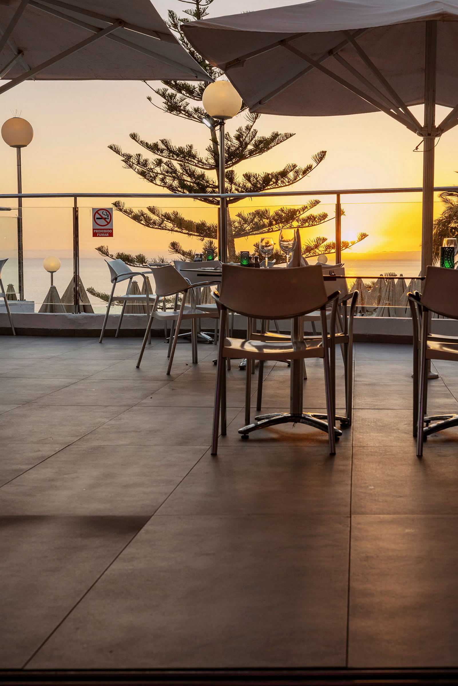 Restaurant med uteservering og havutsikt ved solnedgang. (AI-generert tekst)