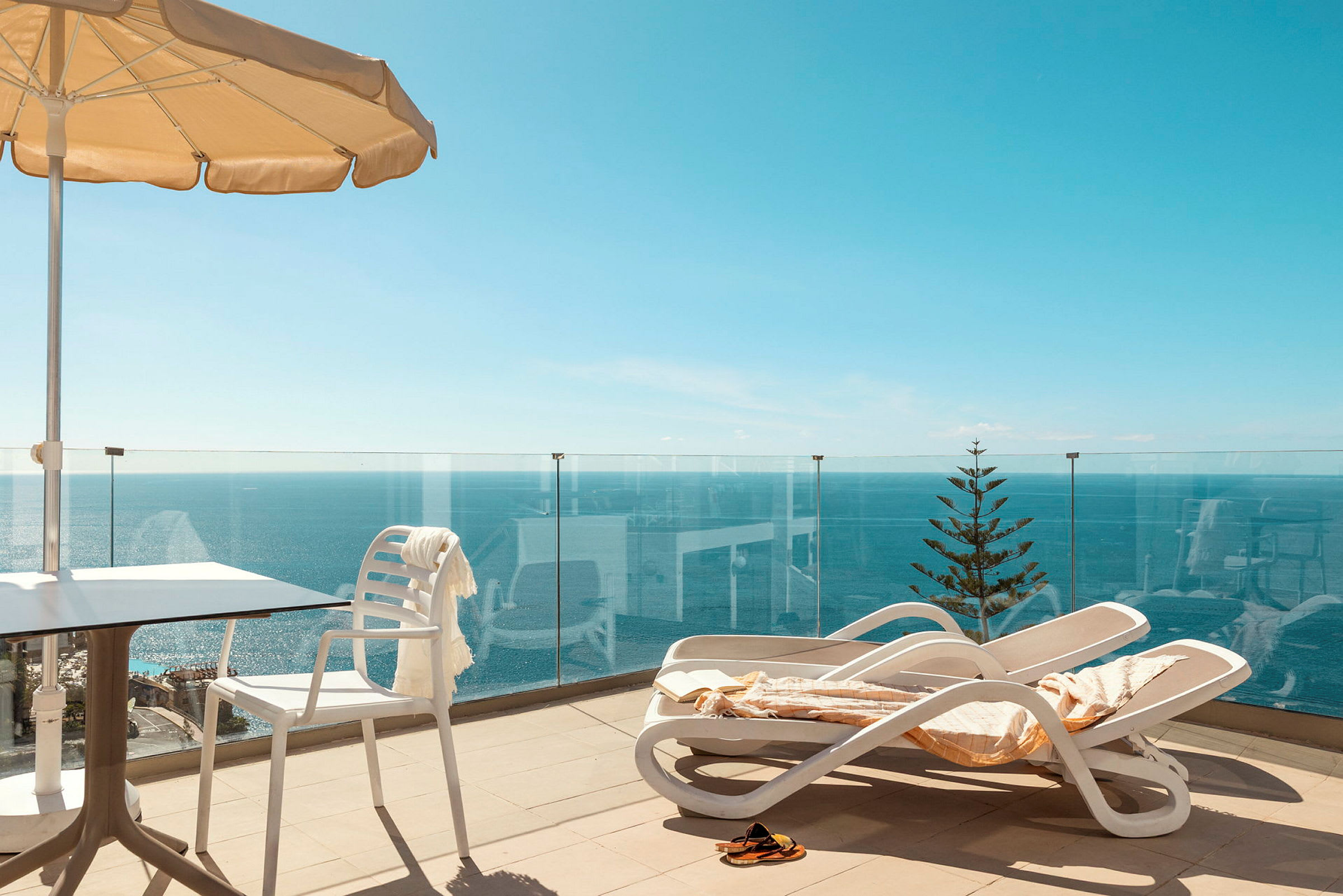 Terrasse med solsenger, parasoll og havutsikt. (AI-generert tekst)