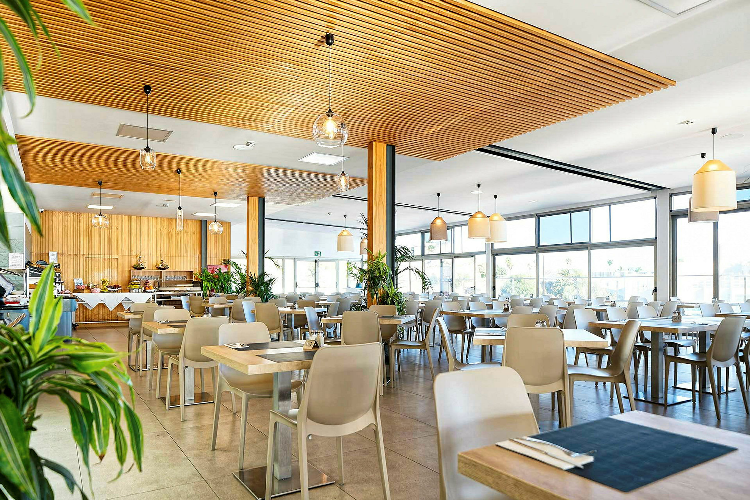 Bilde av en lys restaurant med trepaneler og store vinduer. (AI-generert tekst)