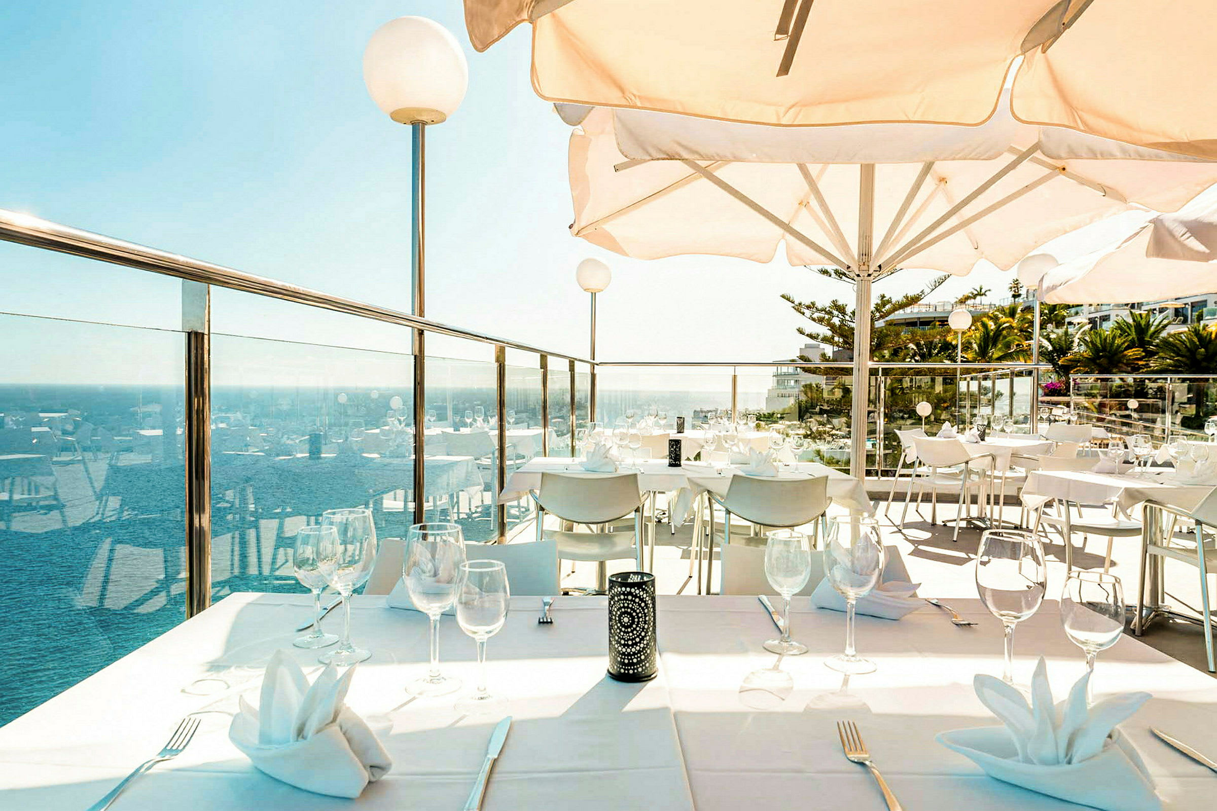 En terrasse med oppsatte bord og utsikt over havet. (AI-generert tekst)