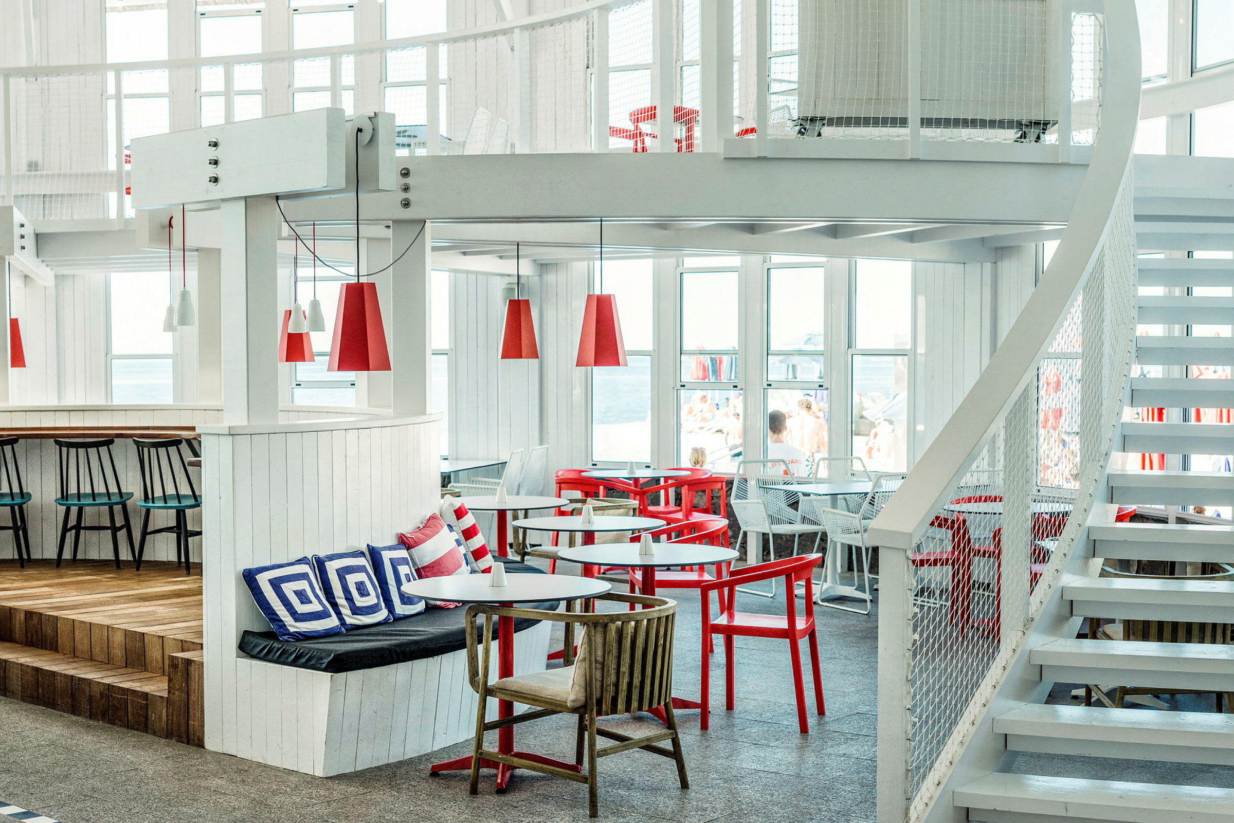 Interiør av en lys og moderne restaurant med røde og hvite møbler. (AI-generert tekst)