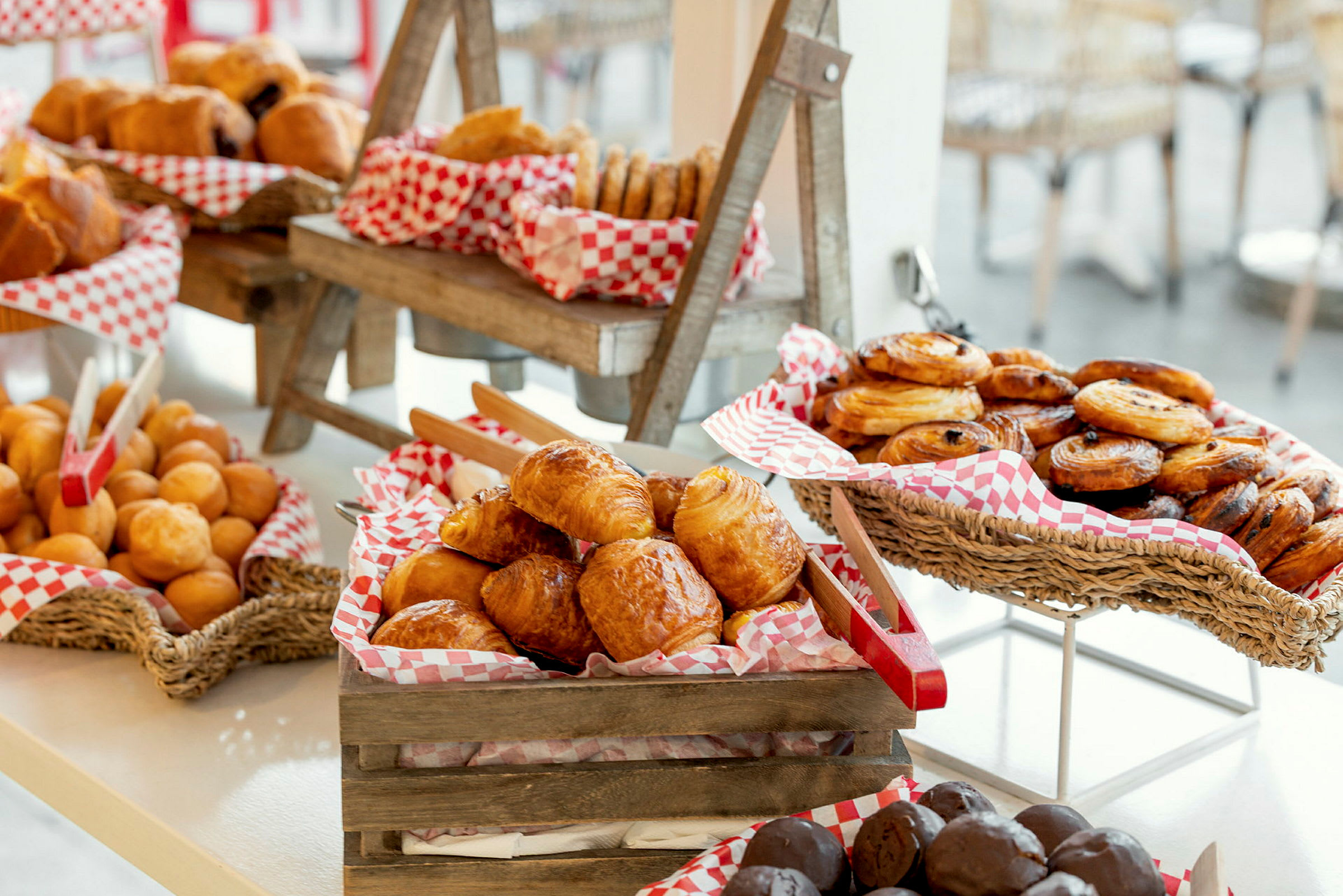 En utstilling med ulike typer bakverk, inkludert croissanter, boller og danske wienerbrød, i kurver og trekasser. (AI-generert tekst)