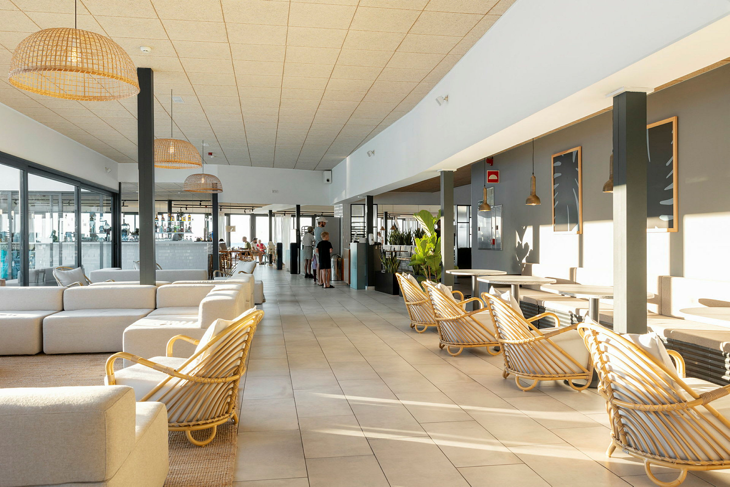 Et solfylt hotellrom med lyse møbler og store vinduer. (AI-generert tekst)