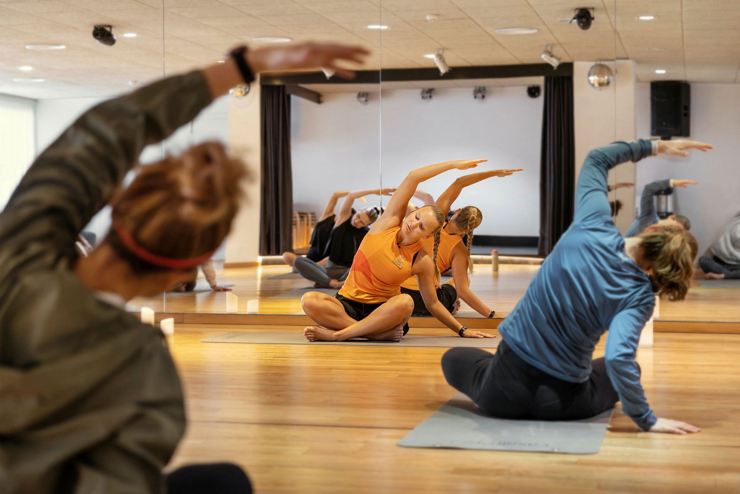 En gruppe mennesker trener yogastillinger i et speilsal. (AI-generert tekst)
